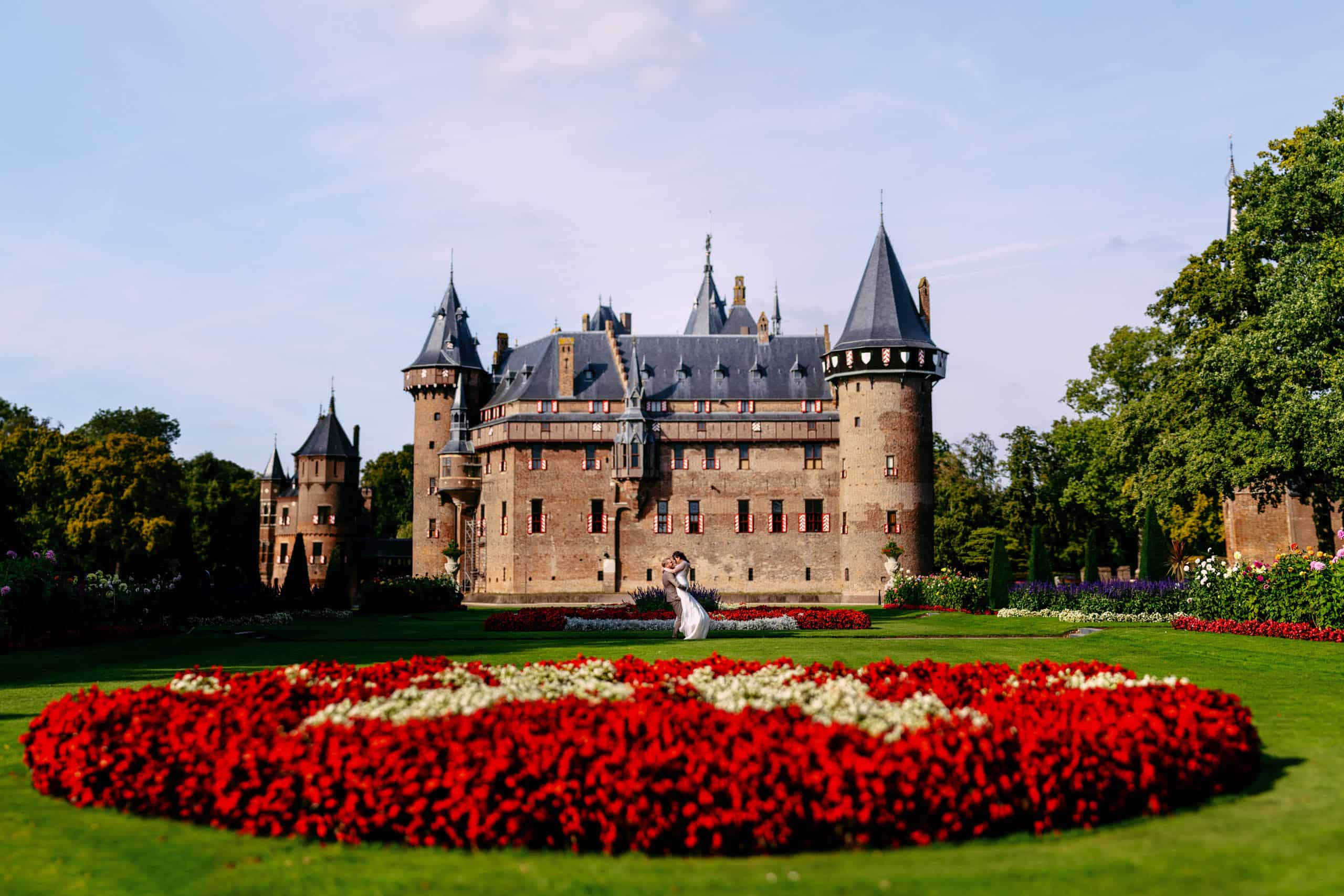 A bride and groom stand in front of a castle, chosen as one of South Holland's most picturesque wedding venues.