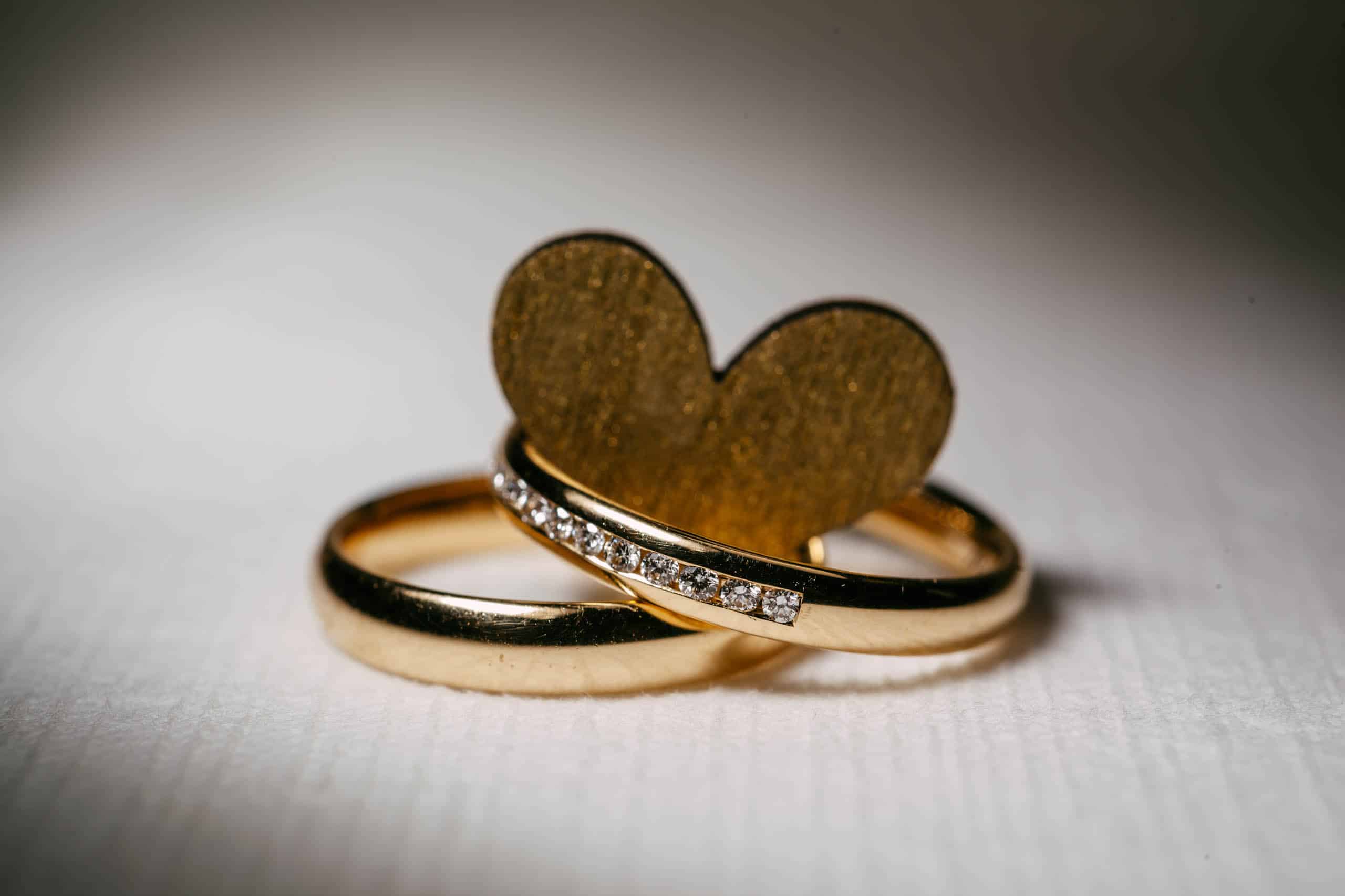 Twee prachtige gouden trouwringen met een hartvormige diamant in het midden, symbool voor mooie trouwdata.