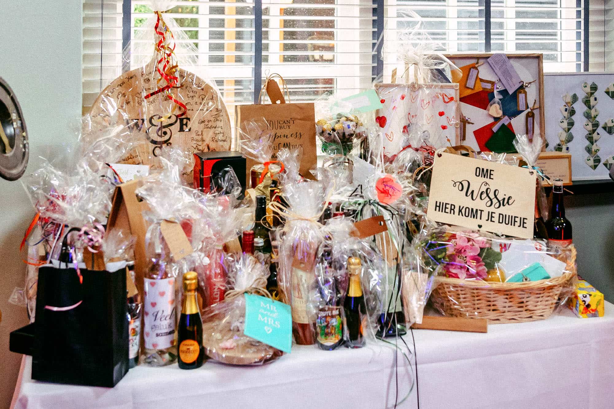 A table with a lot of gift bags on it, containing various items for a wedding party.