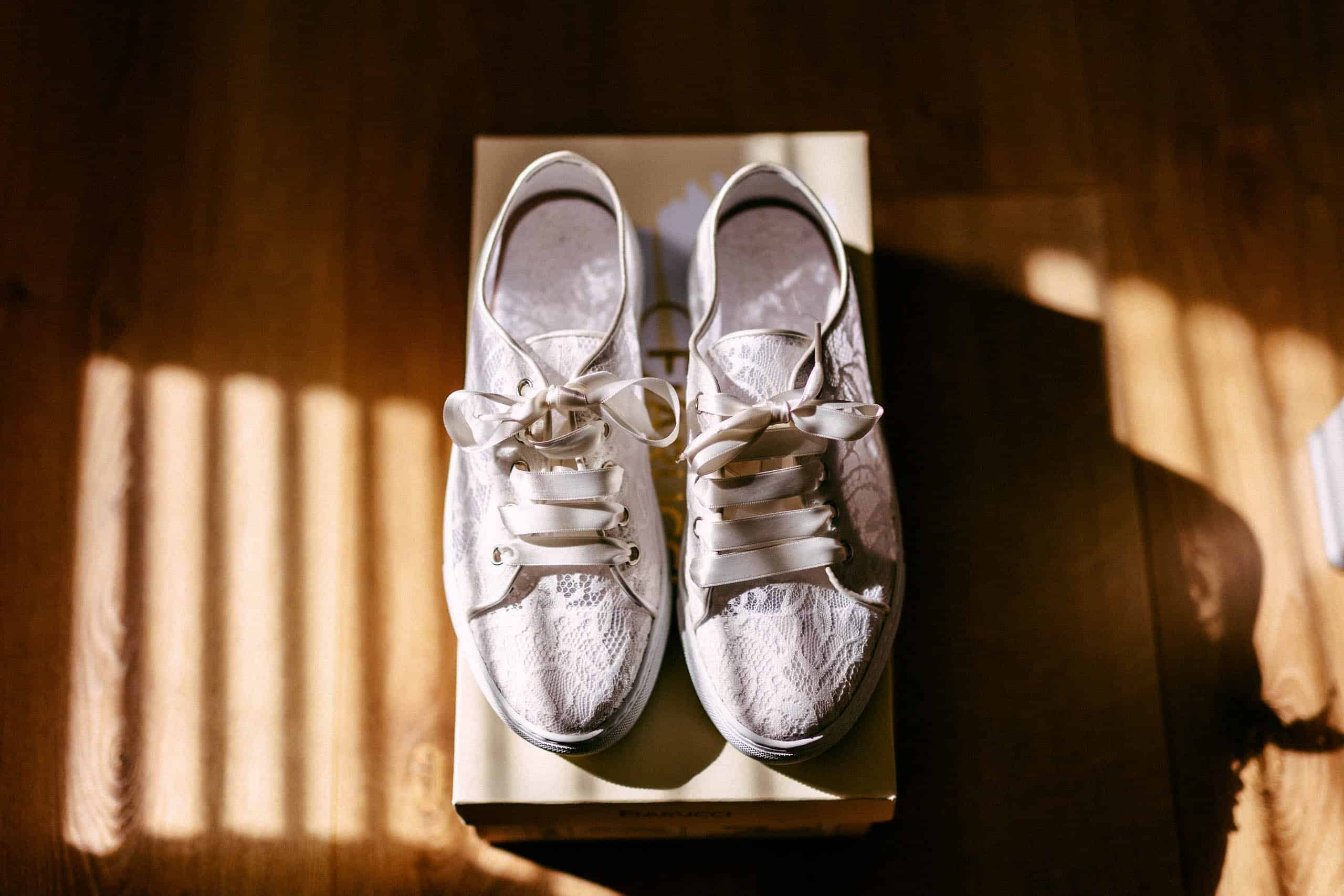 A pair of comfortable white wedding shoes atop a box.