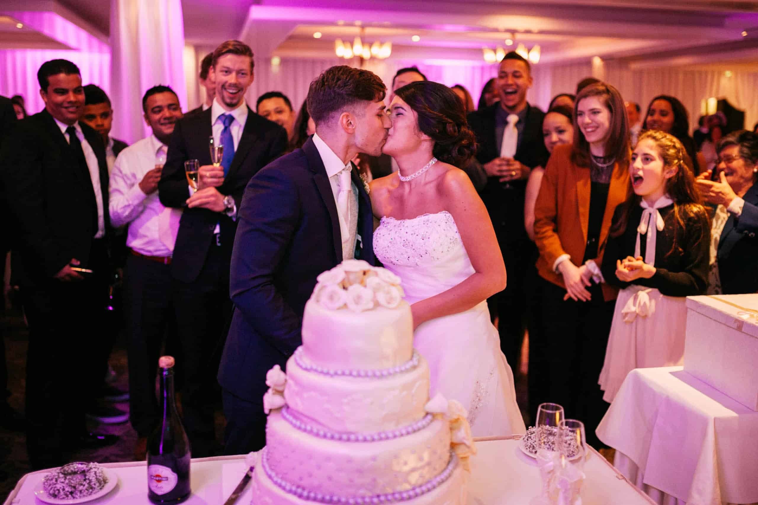 A bride and groom kissing in front of their wedding cakes.