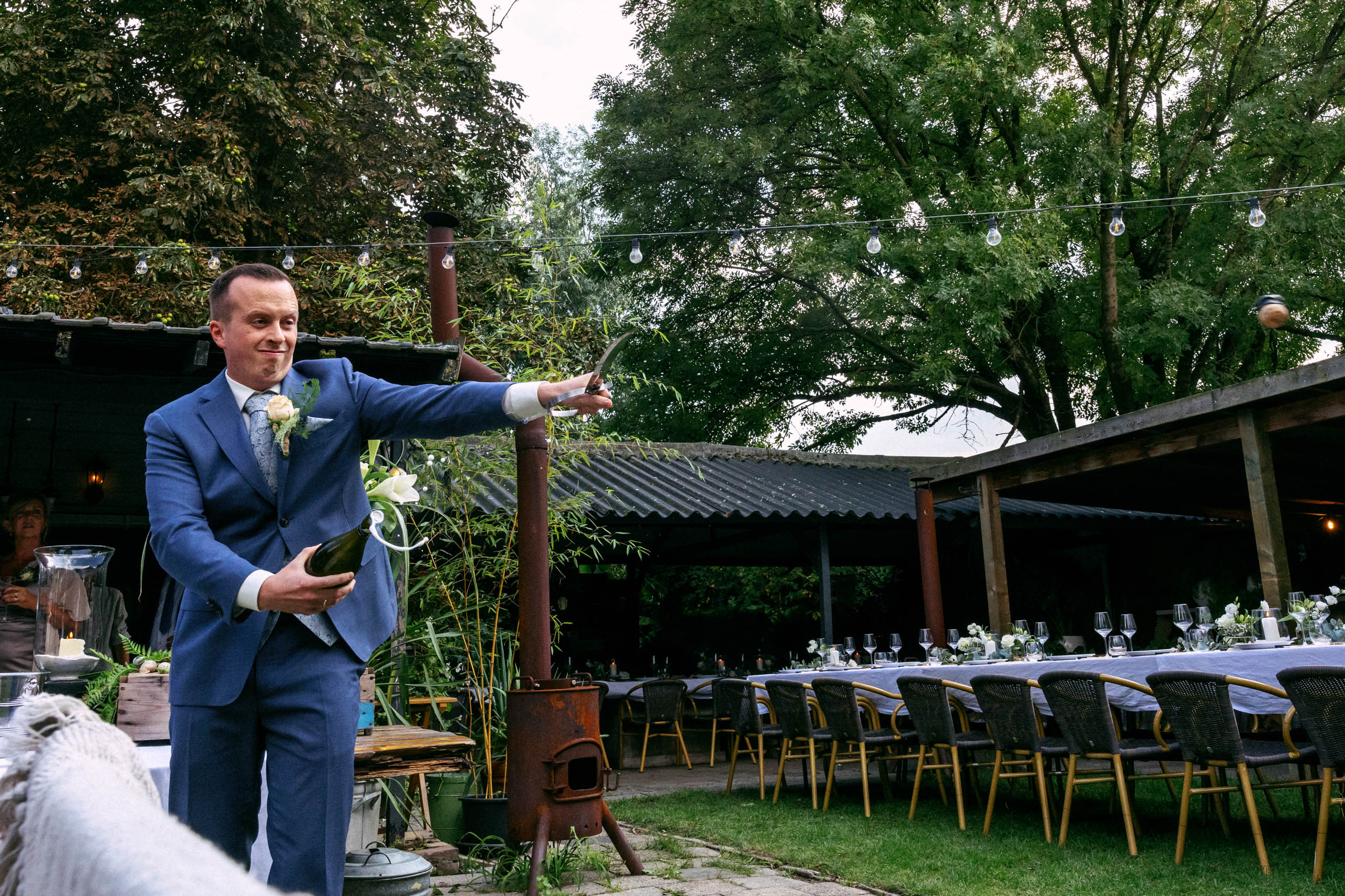 Een man in een blauw pak houdt een boeket vast op een Nederlandse bruiloft.