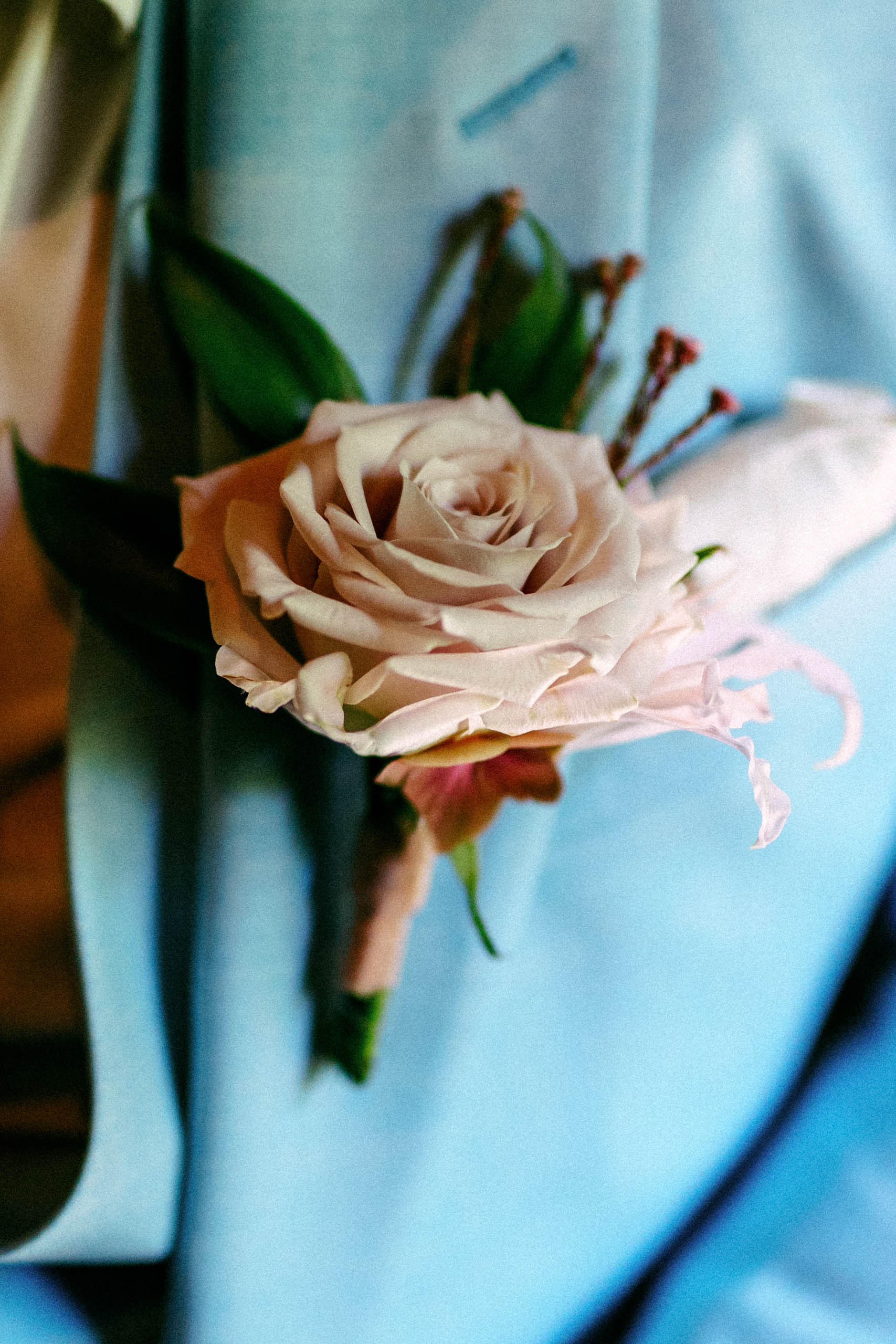 Corsage met een roze roos en gipskruit aan de bruidegom.