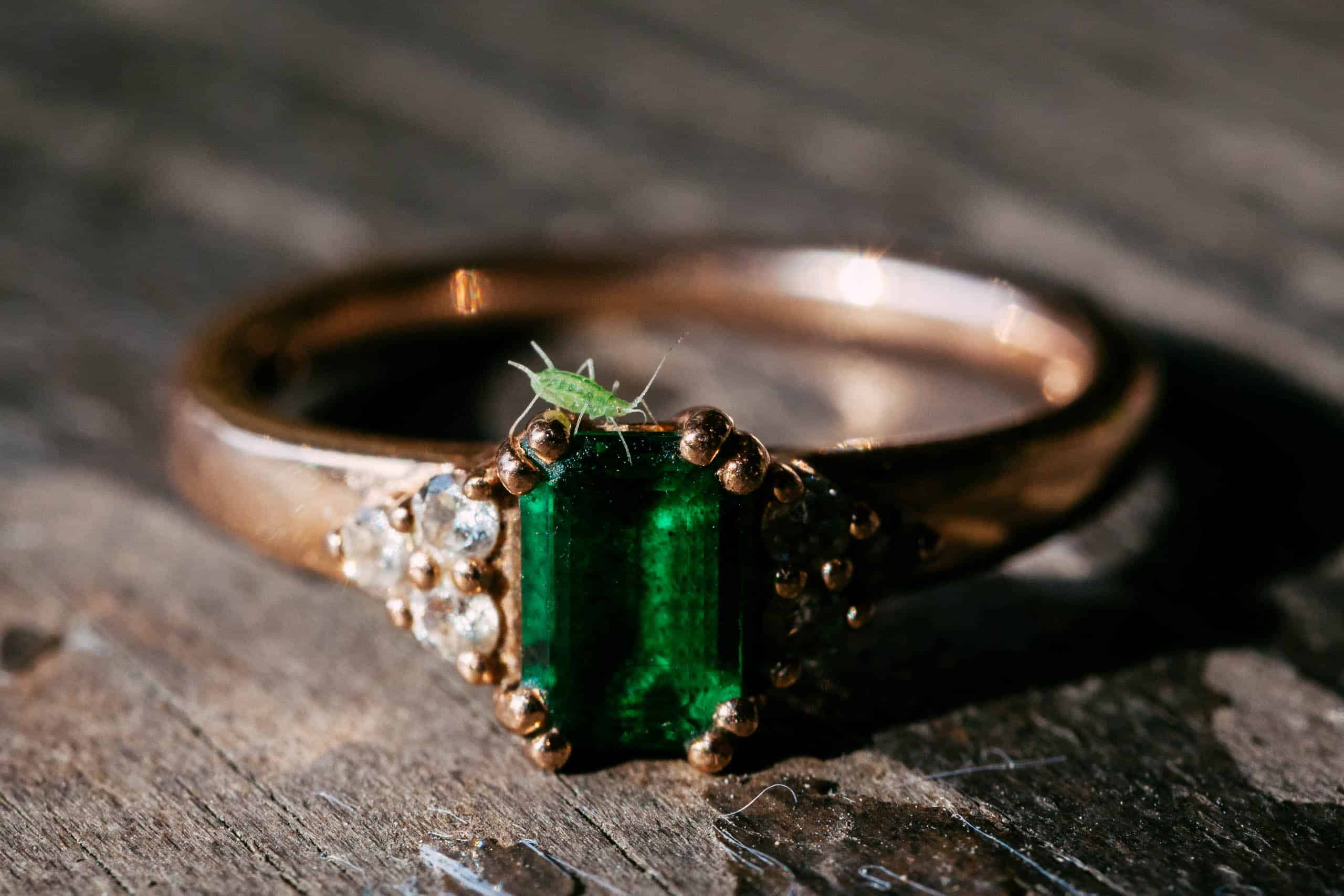 Een prachtige smaragd geslepen verlovingsring die elegant op een houten tafel rust.