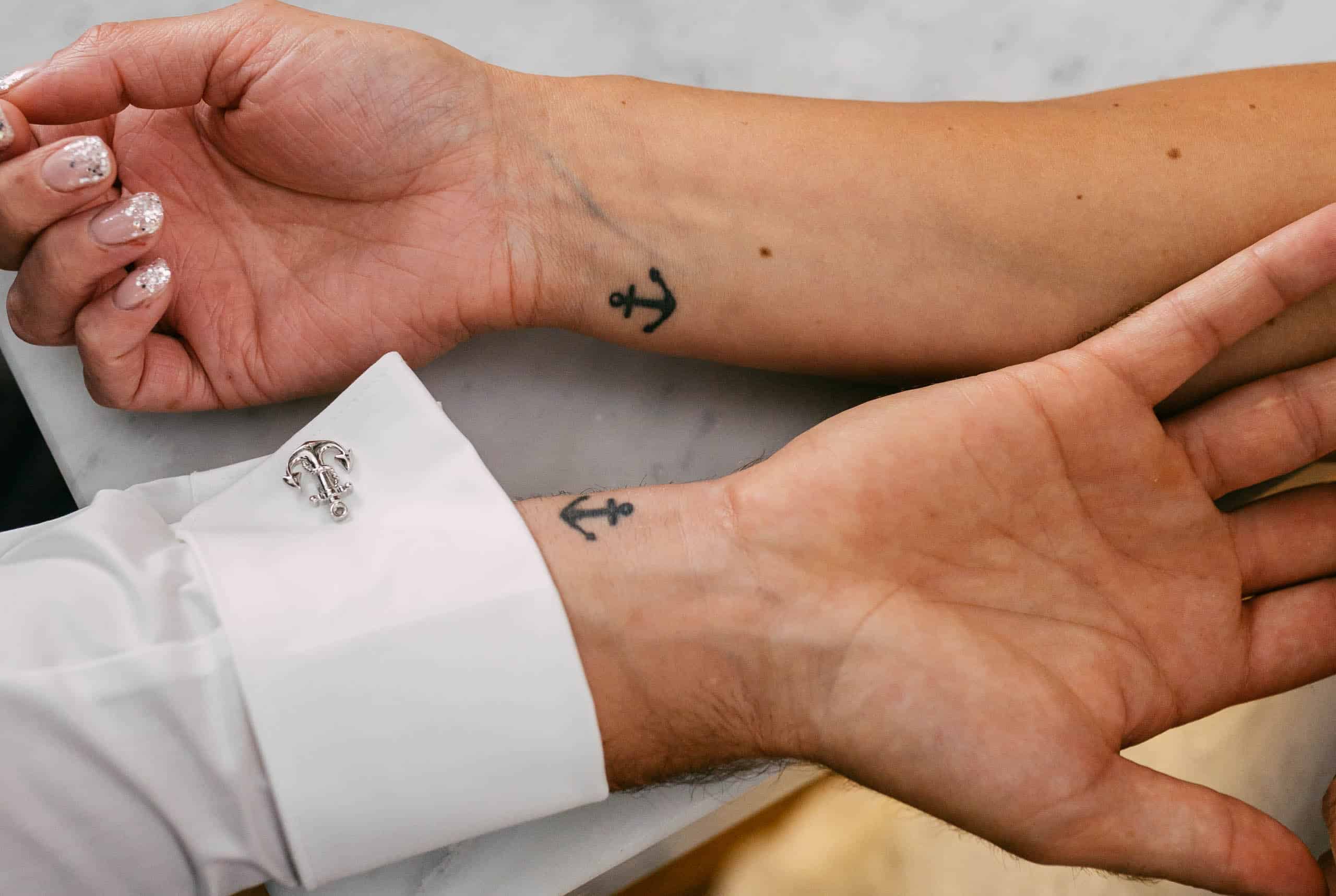 A couple with small tattoos on their wrists, with a wedding theme.
