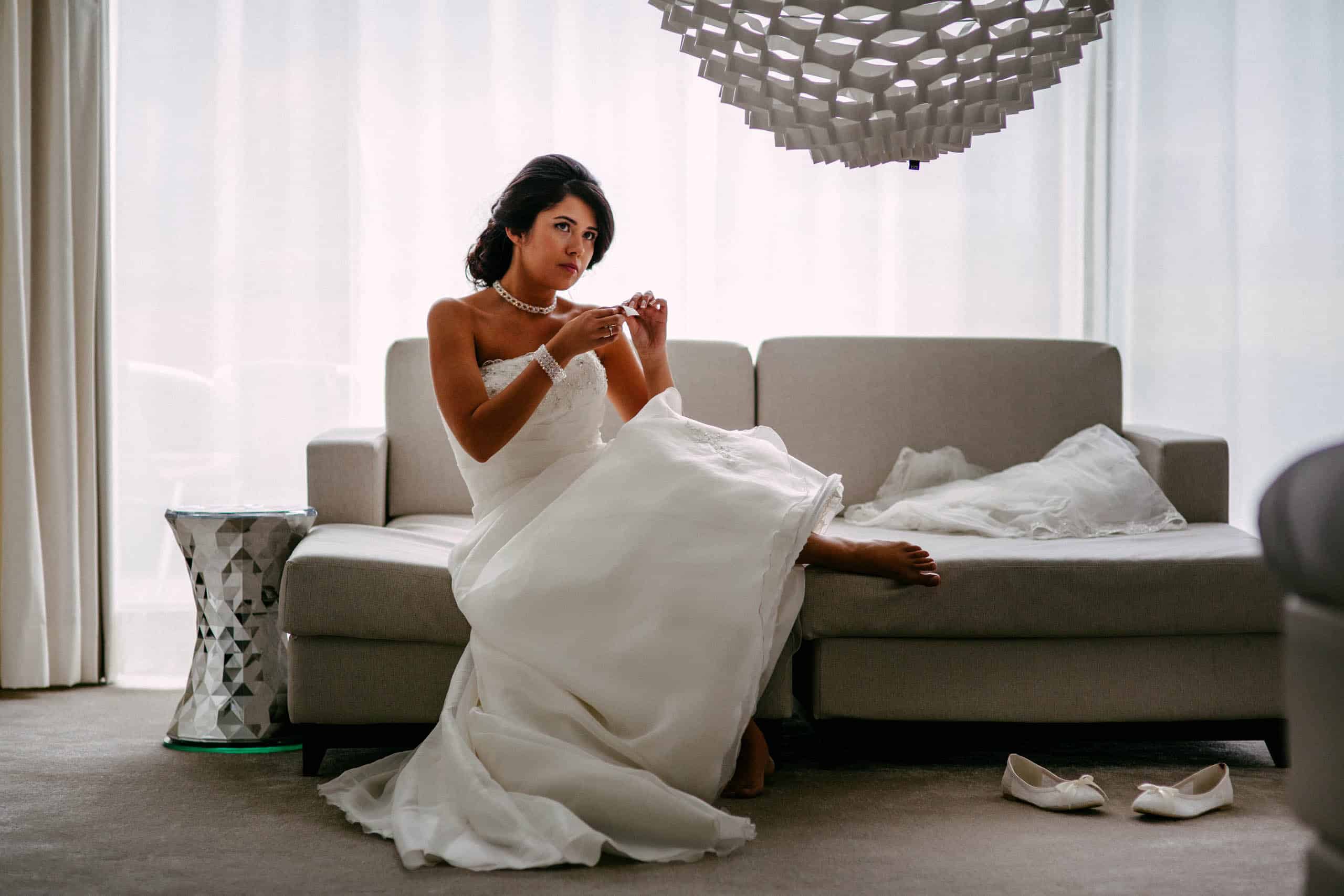 A bride sitting on a sofa in a wedding dress, carefully inspecting for stains and thinking about ways to remove them from your wedding dress