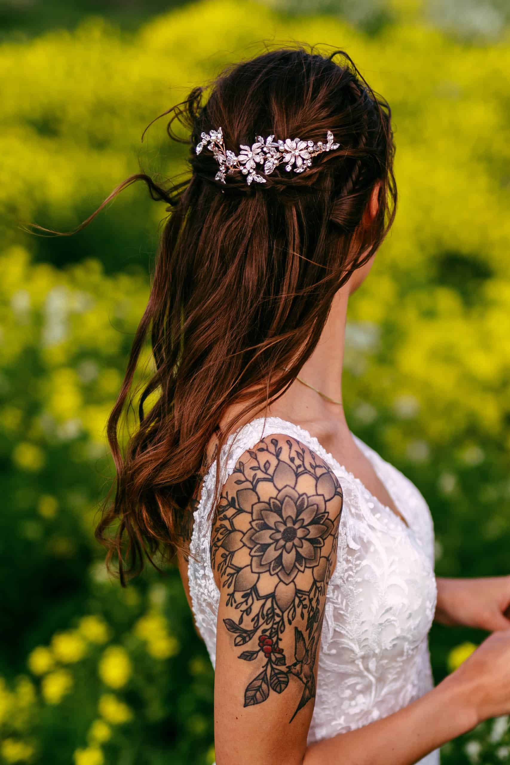 Een bruid met tatoeages in een veld.
