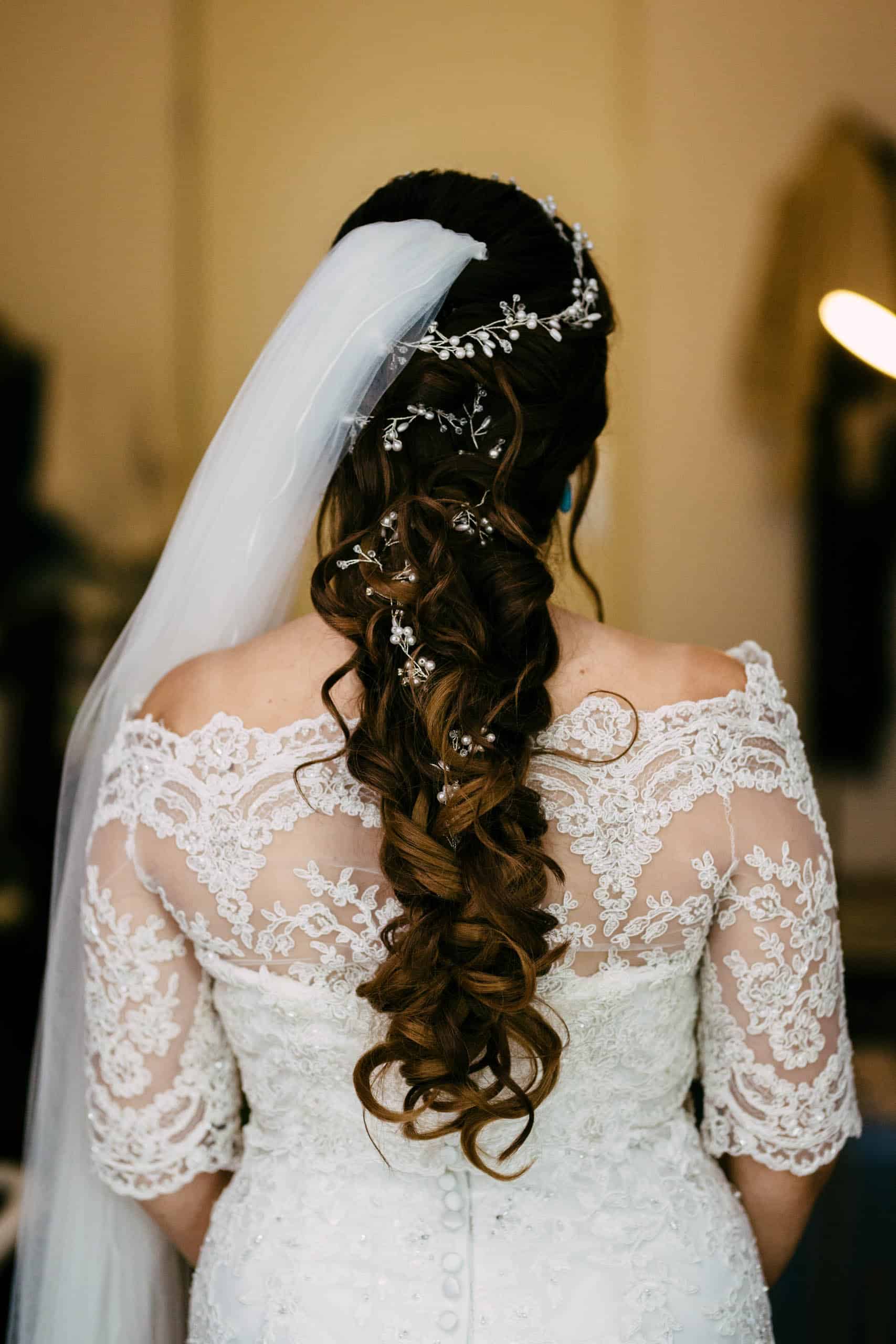 Een mooie bruid met lang haar en een sluier met elegante bruidskapsels.