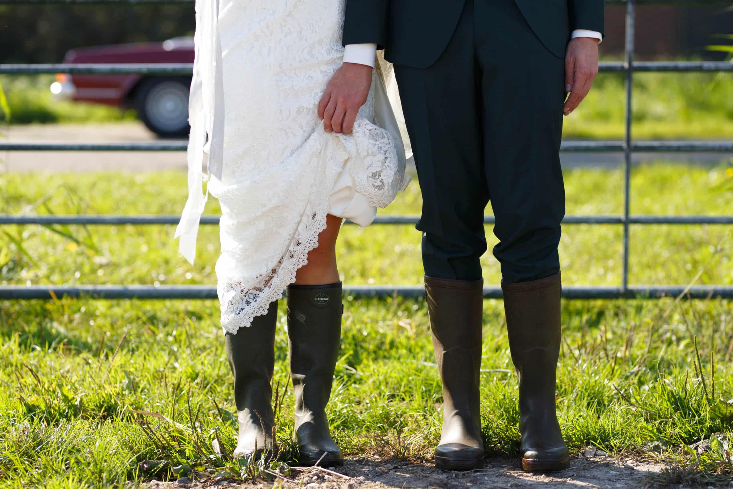 Een bruid en bruidegom staan comfortabel voor een hek.