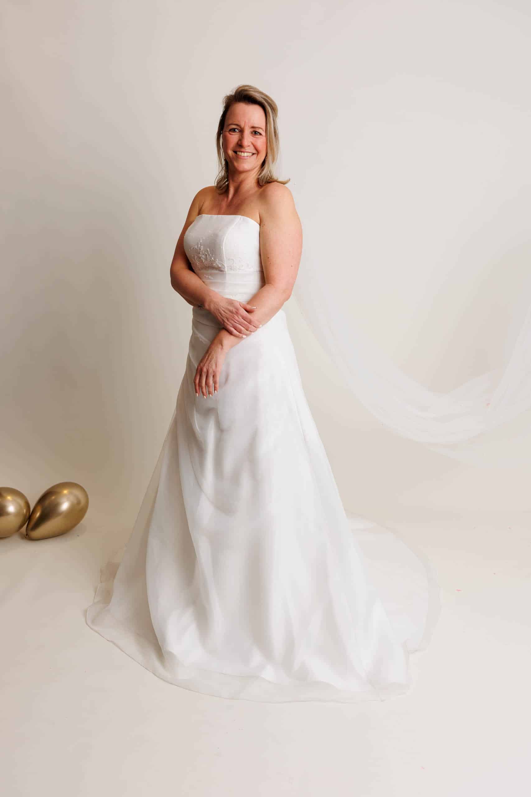 A woman in a wedding dress poses for a photo while trying on wedding dresses.