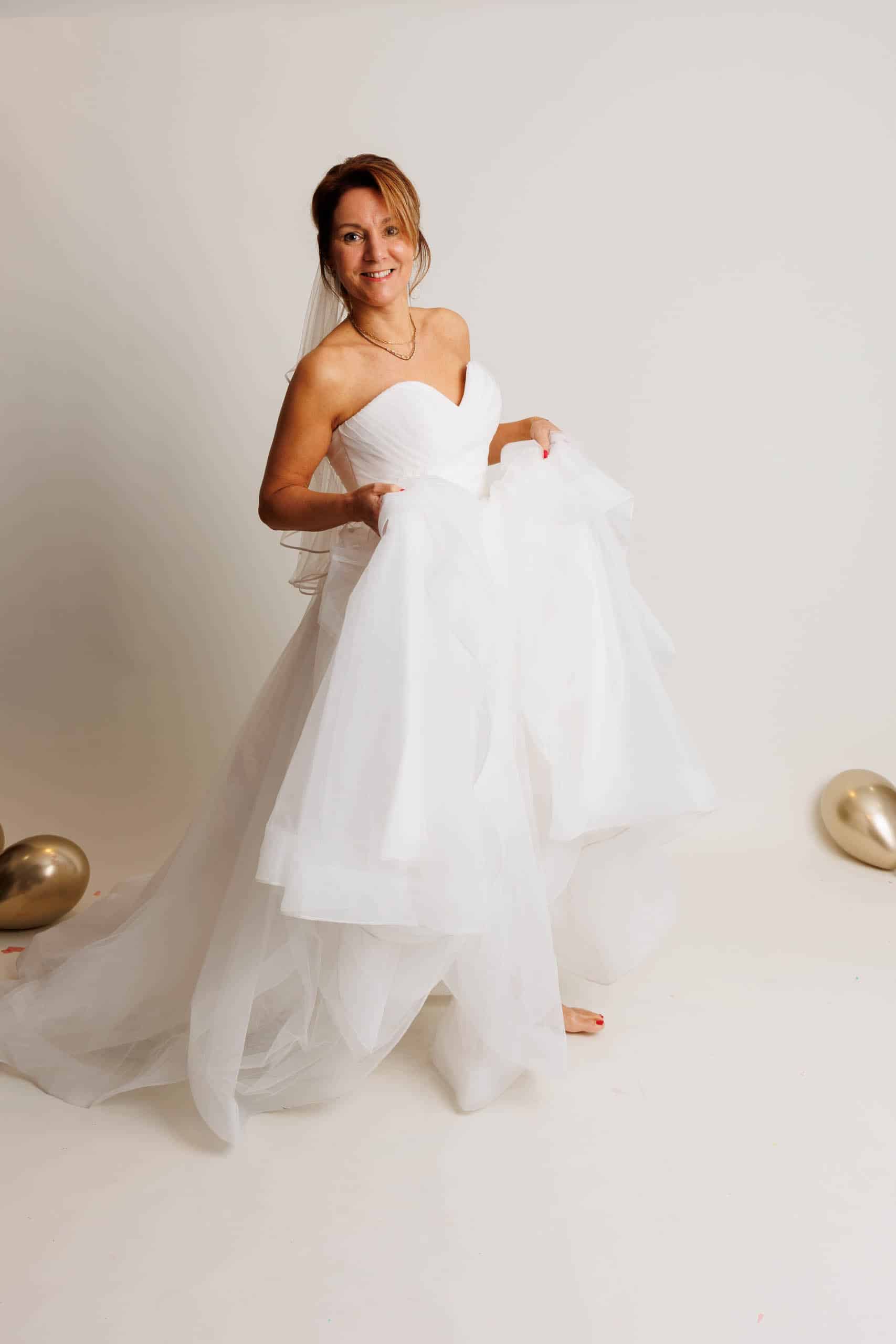 Een bruid in een trouwjurk poseert voor een foto terwijl ze trouwjurken past voor de lol.