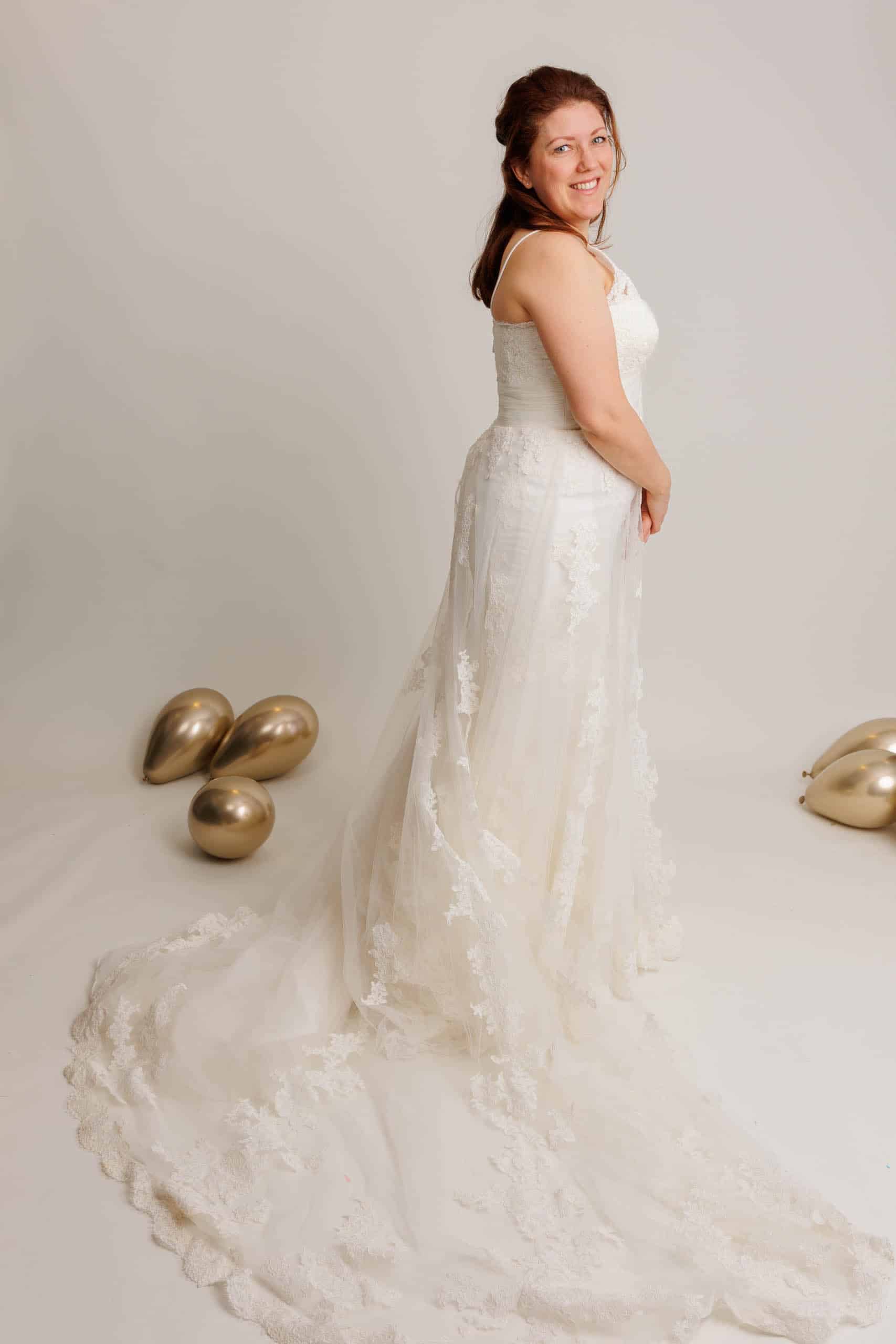 Een vrouw in trouwjurk poseert voor een leuke foto terwijl ze trouwjurken past.