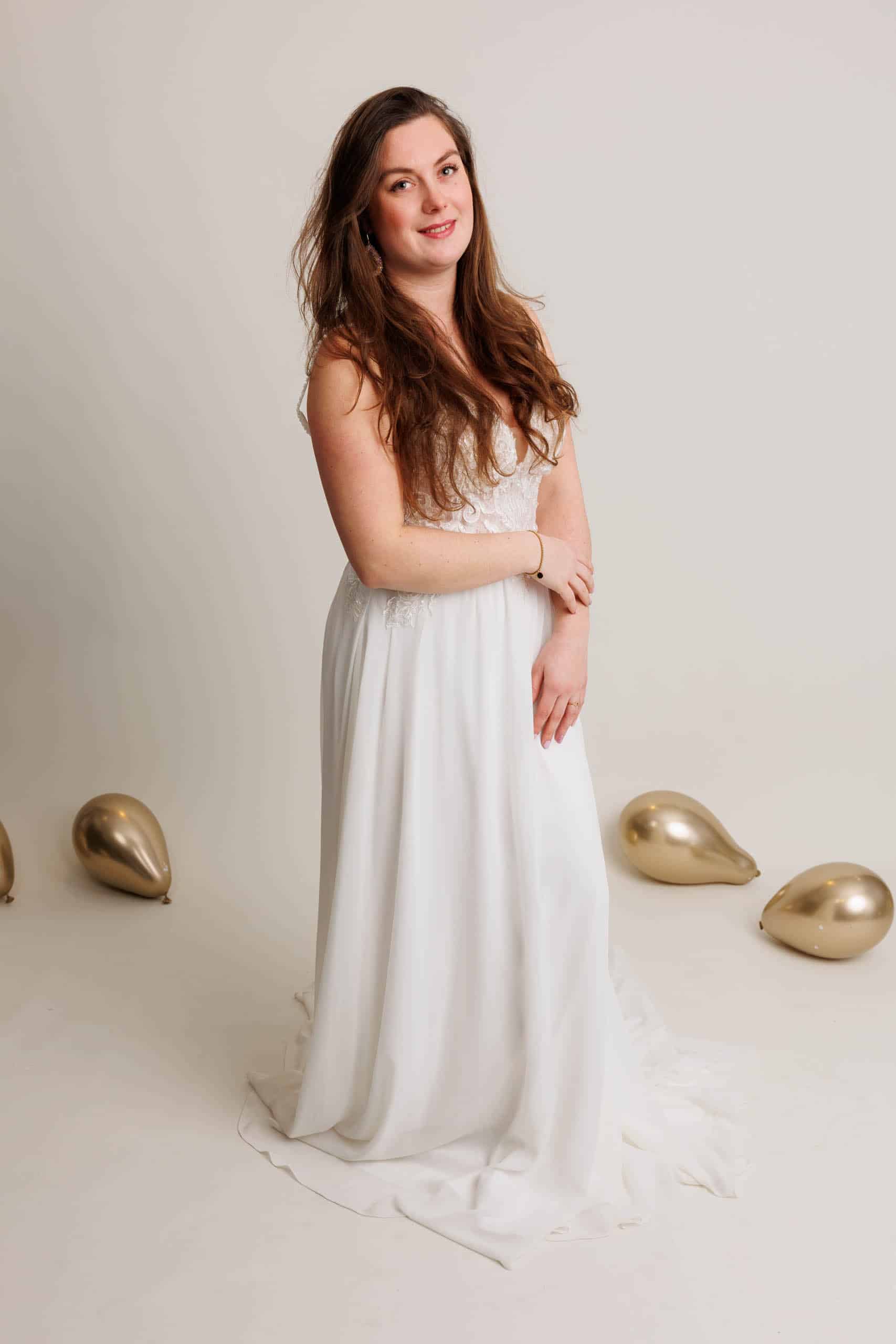 Een vrouw in een witte trouwjurk poseert voor een foto.