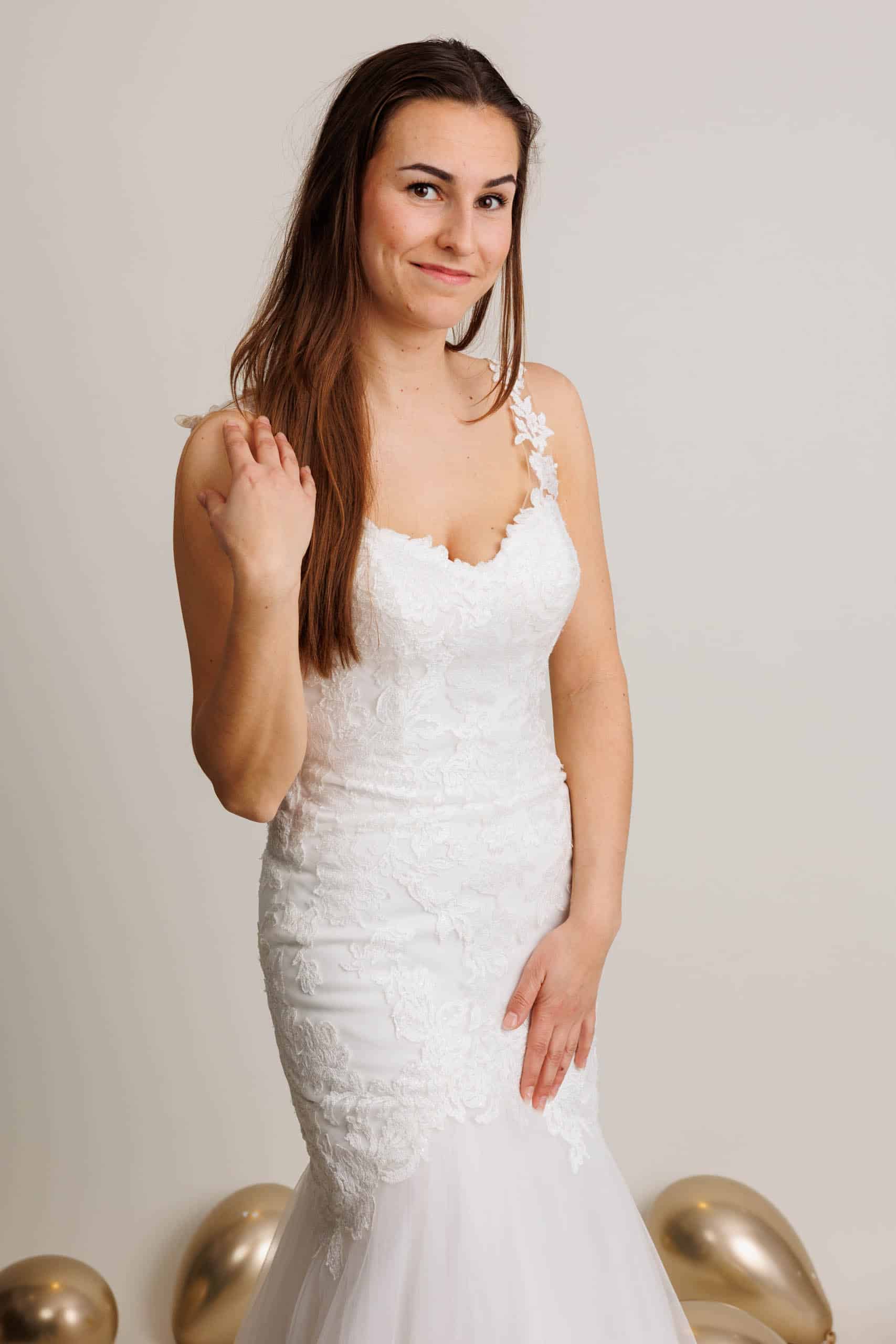 Een mooie vrouw in een trouwjurk poseert voor een foto terwijl ze trouwjurken past voor de lol.