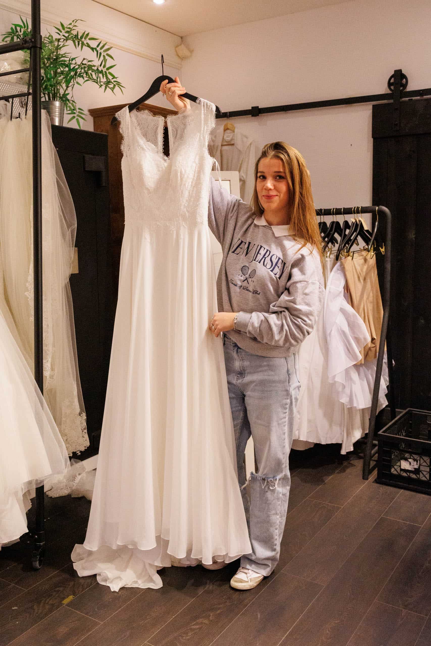 A woman playfully trying on wedding dresses in a shop.