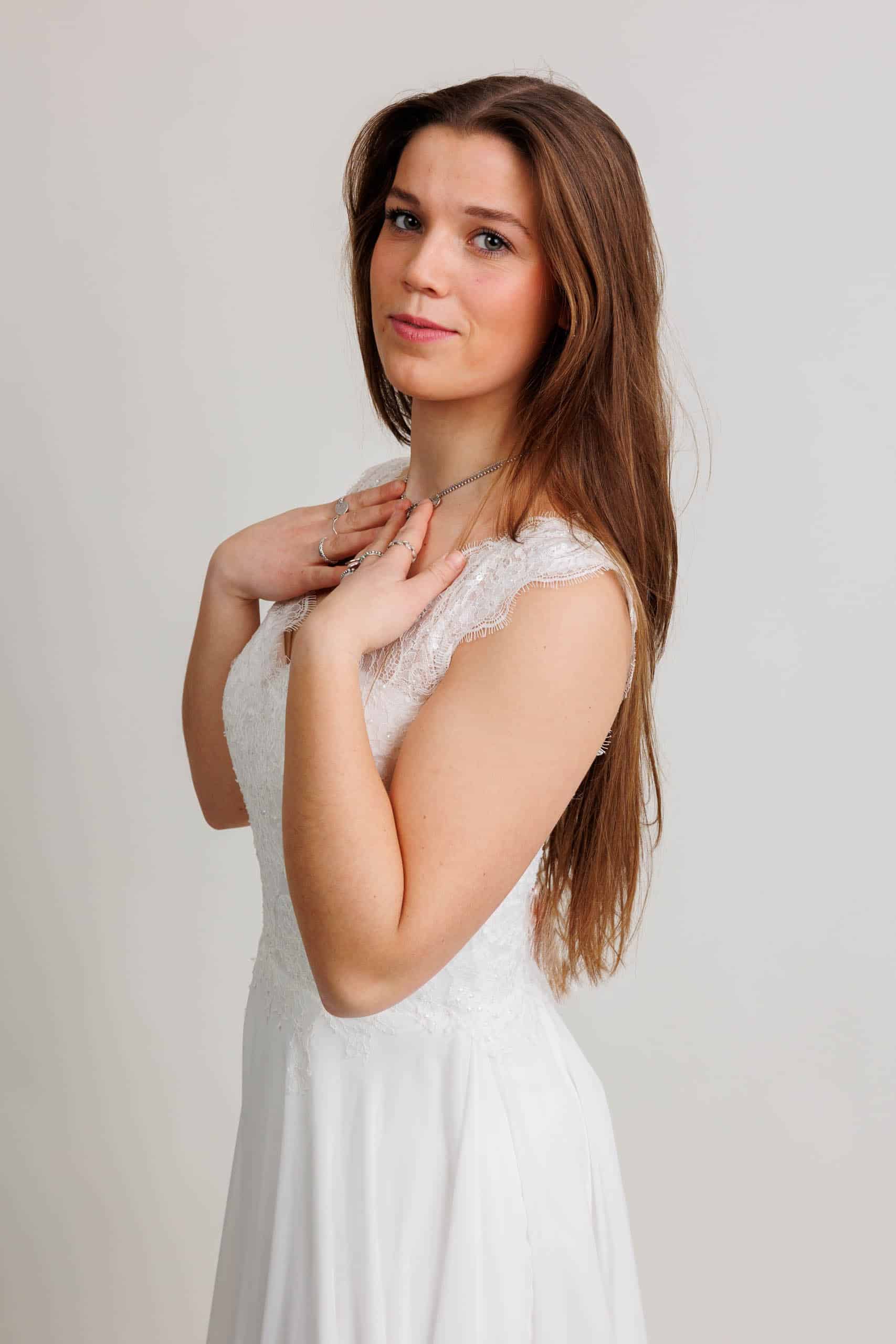 Een jonge vrouw in een witte jurk poseert voor een foto terwijl ze voor de lol trouwjurken past.