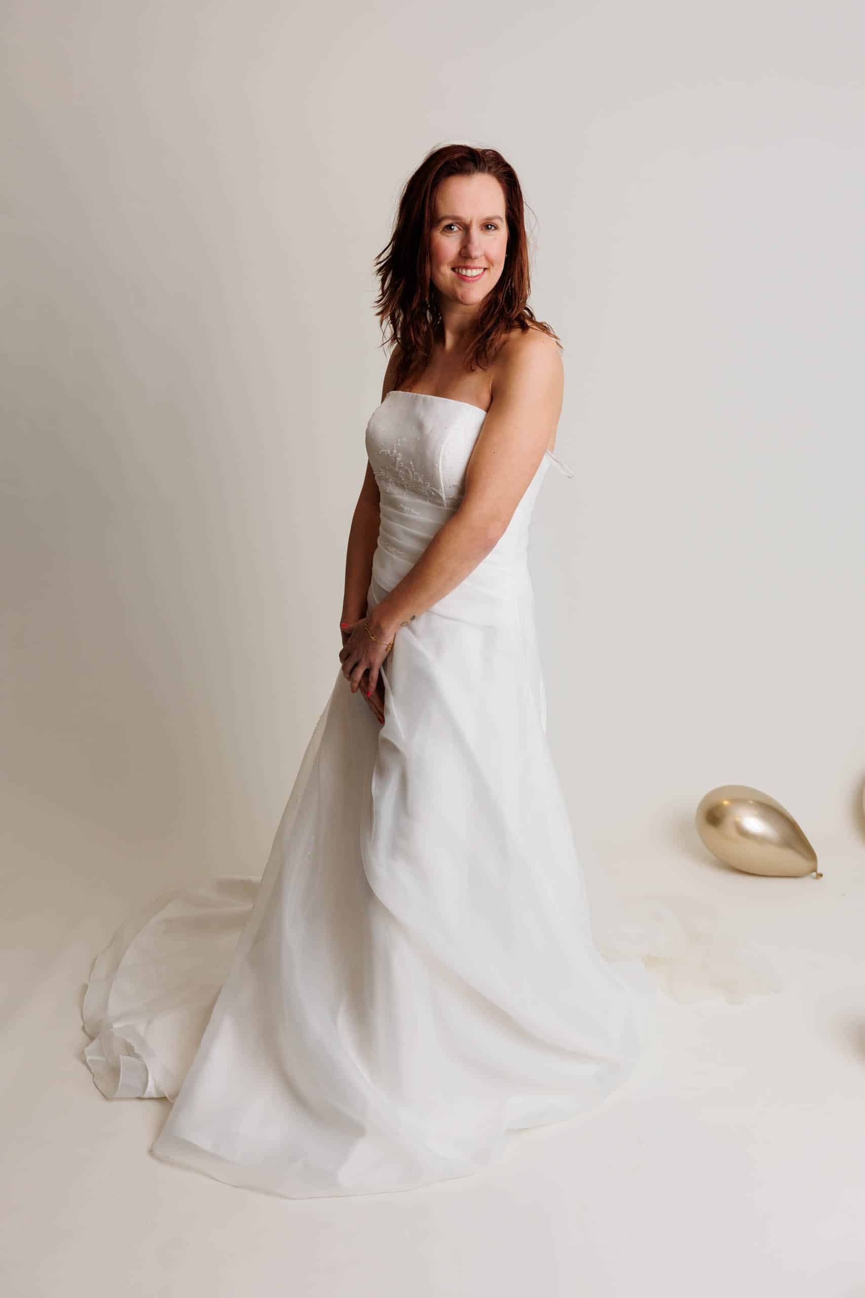 Een vrouw in een trouwjurk poseert voor een foto, terwijl ze trouwjurken past voor de lol.
