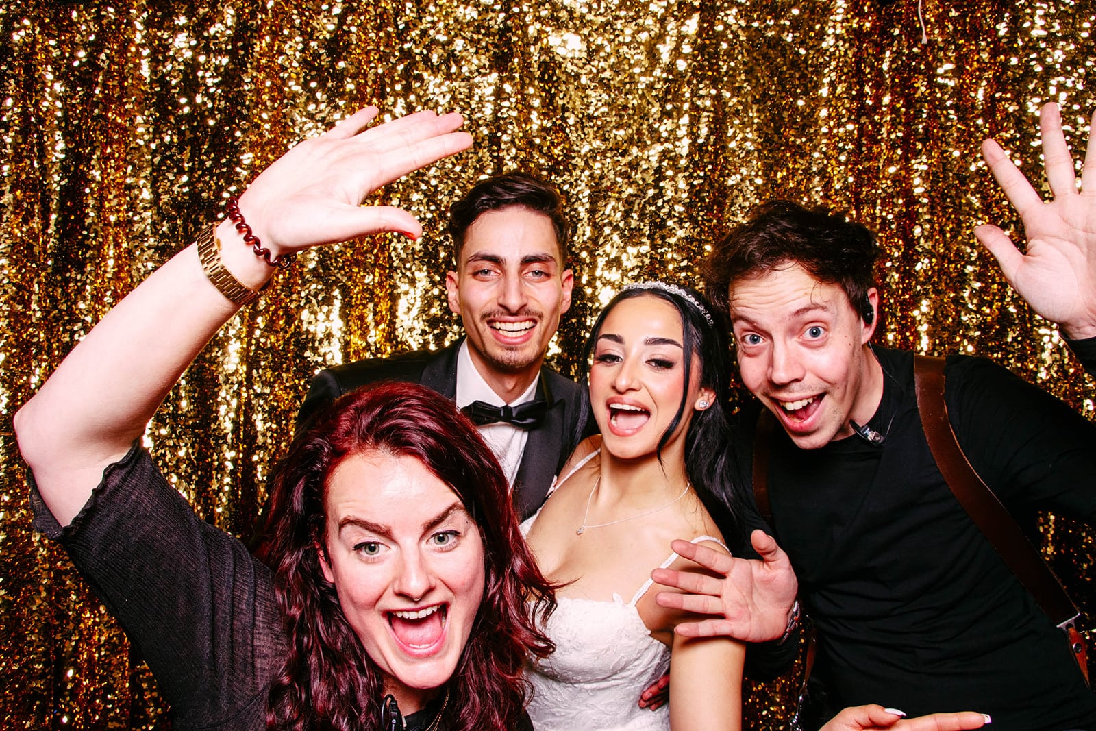 About us: A group of people pose for a picture in a golden photo booth.
