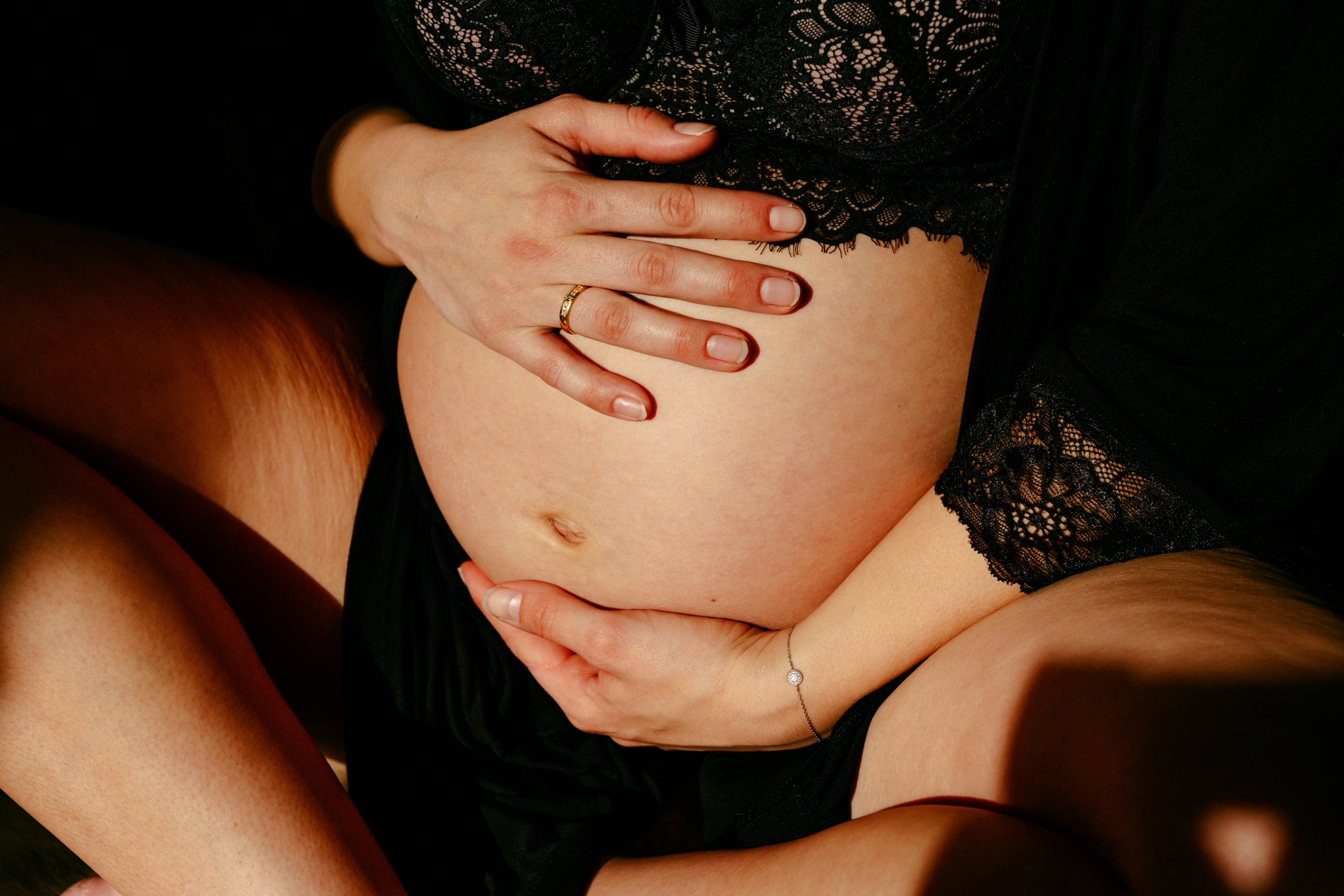 Een Zwangerschapsshoot waarin het tedere moment van een zwangere vrouw wordt vastgelegd terwijl ze haar buik omhelst.