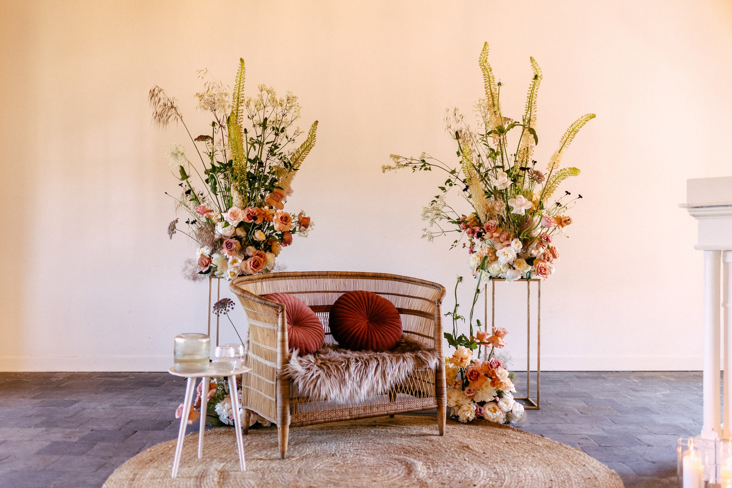 Een rieten stoel met bloemen midden in een kamer, perfect geschikt voor een bruiloftsthema.