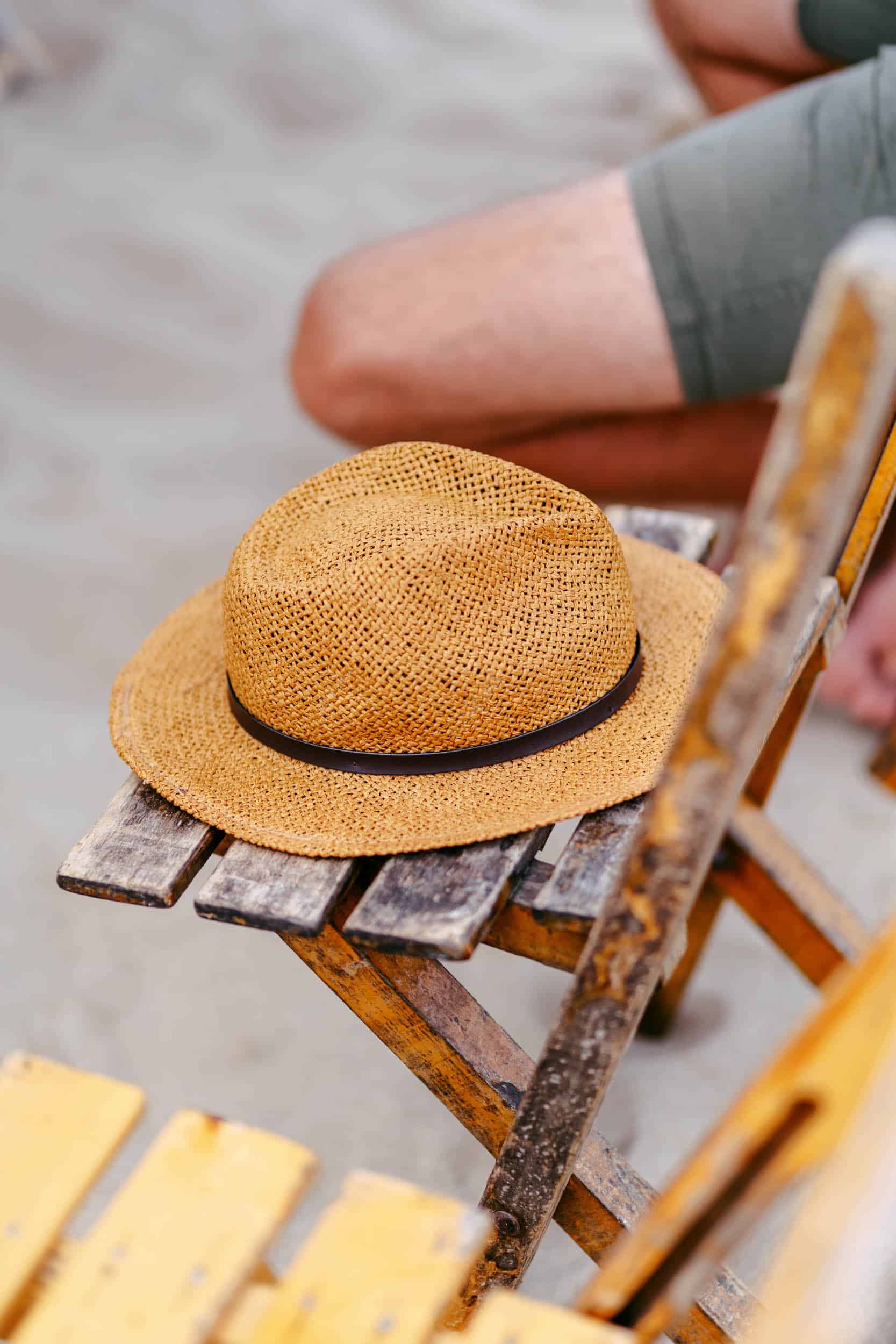 Een man zit op een strandstoel met een hoed erop en geniet van het perfecte trouwlandschap.