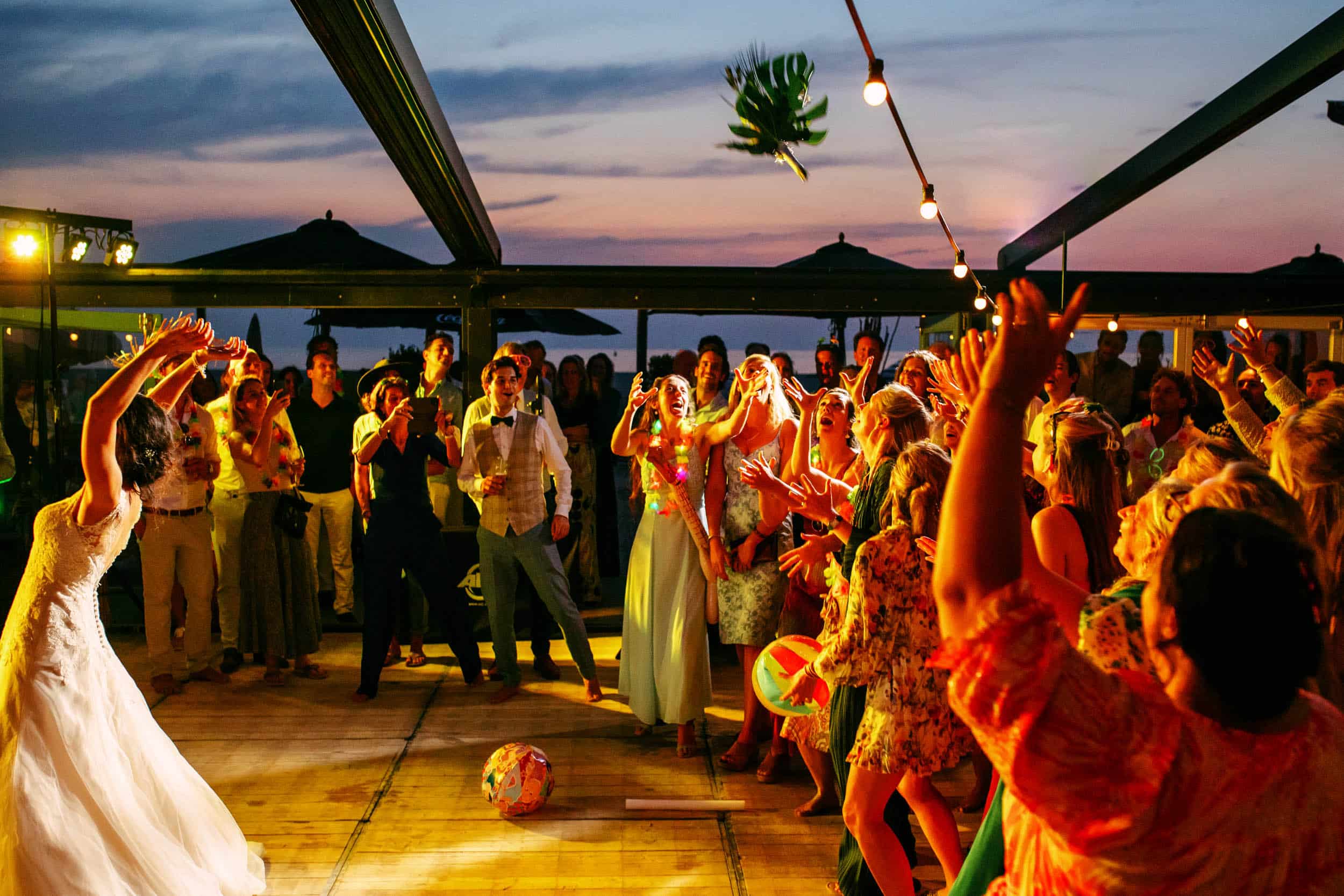 A bride and groom celebrate their marriage by throwing confetti in the air during a beach wedding reception.
