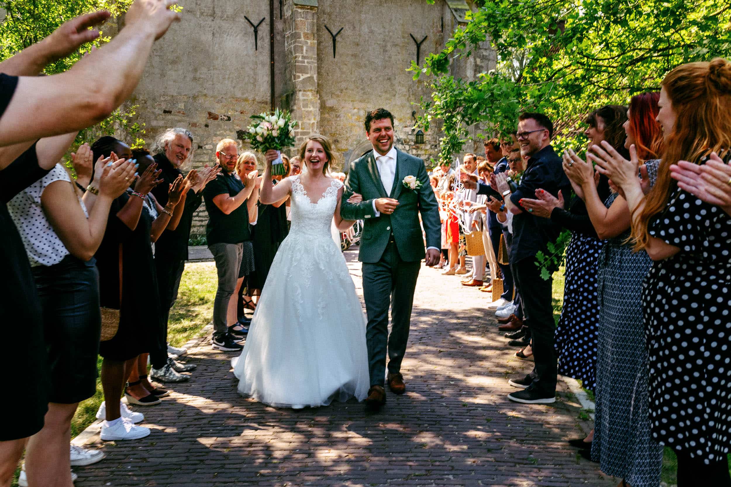 A bride and groom walking down a path in front of a crowd of people during their budget wedding.