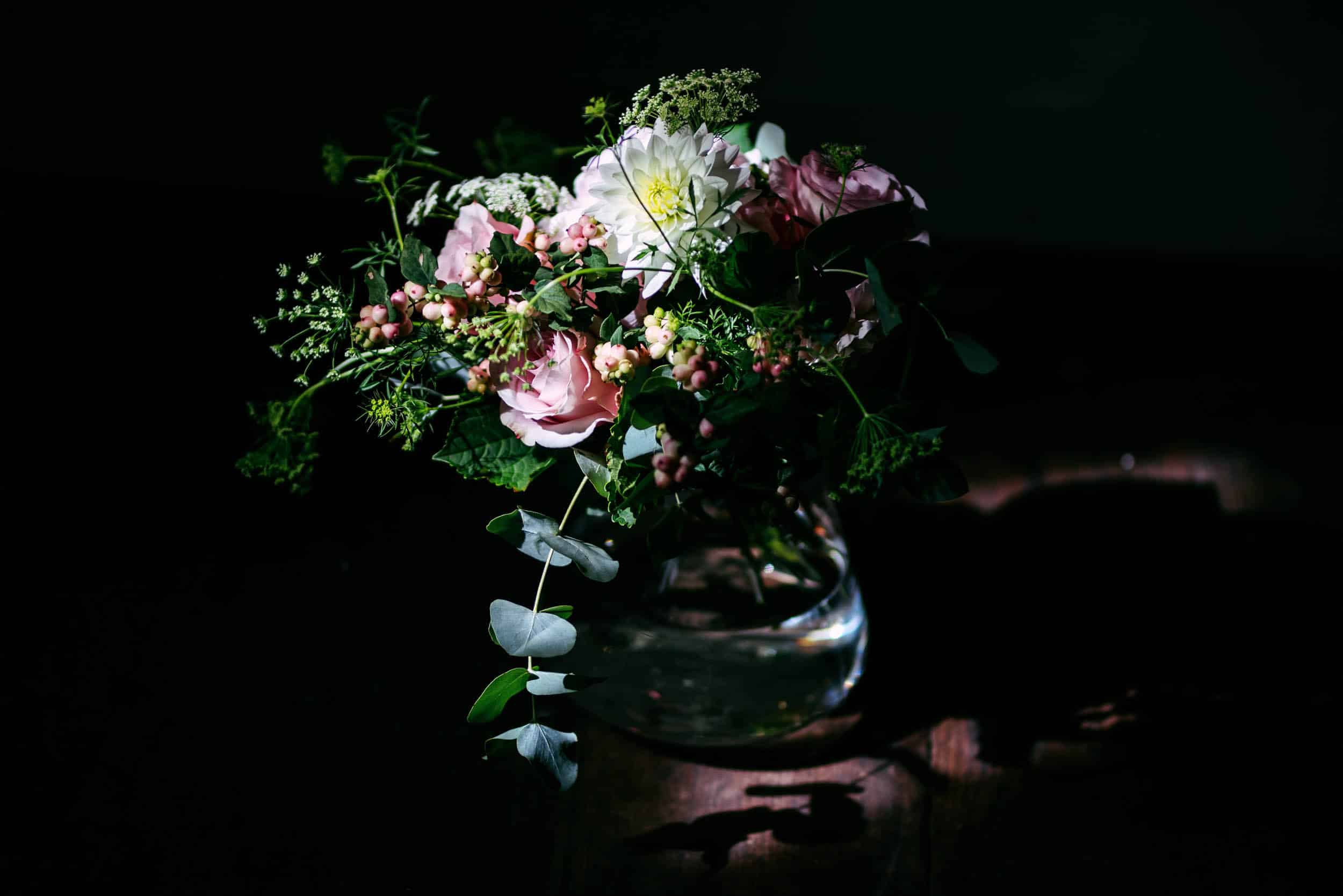 Een boeket bloemen zittend op een tafel in het donker bij Slot Moermond tijdens een huwelijksreceptie.