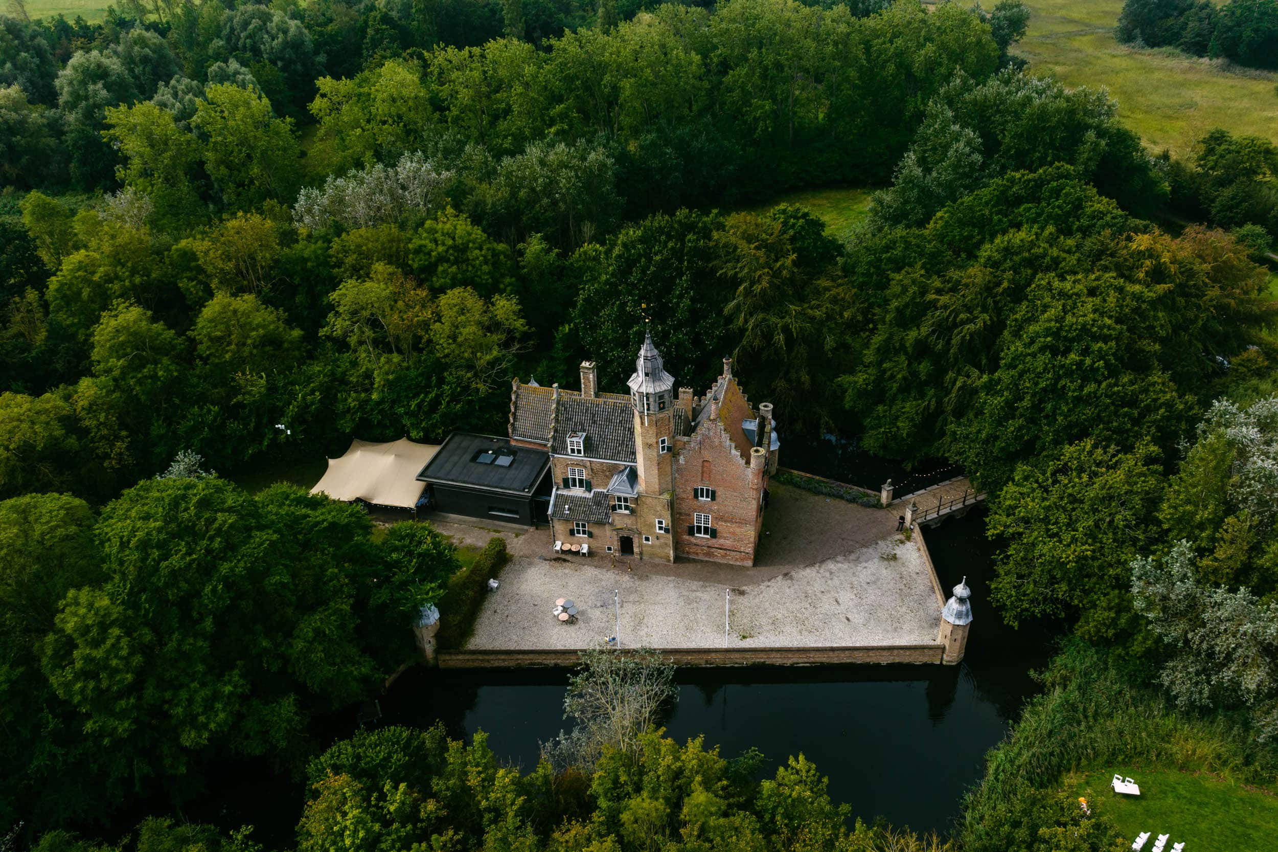 Een luchtfoto van Slot Moermond, een majestueus kasteel te midden van weelderige bomen, een perfecte locatie voor onvergetelijke huwelijksceremonies.