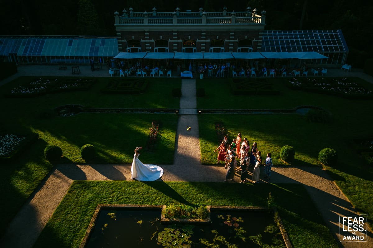 Een bekroonde luchtfoto van een huwelijksfeest in een prachtig aangelegde tuin.