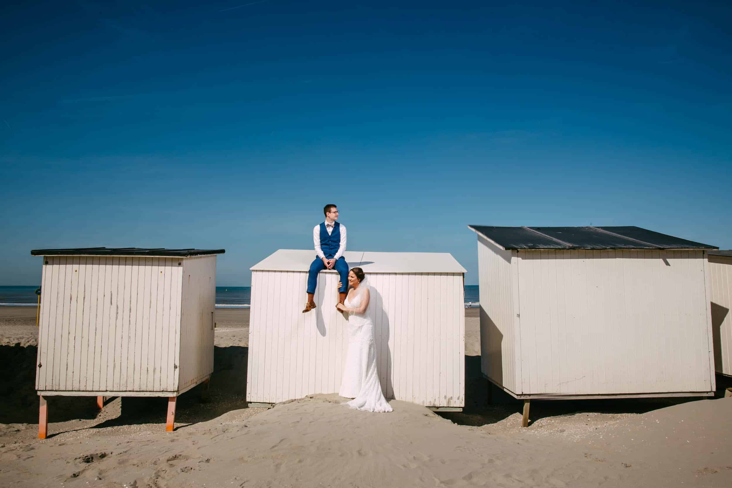 A bride and groom standing atop beach huts, capturing the charming elements of a seaside wedding.