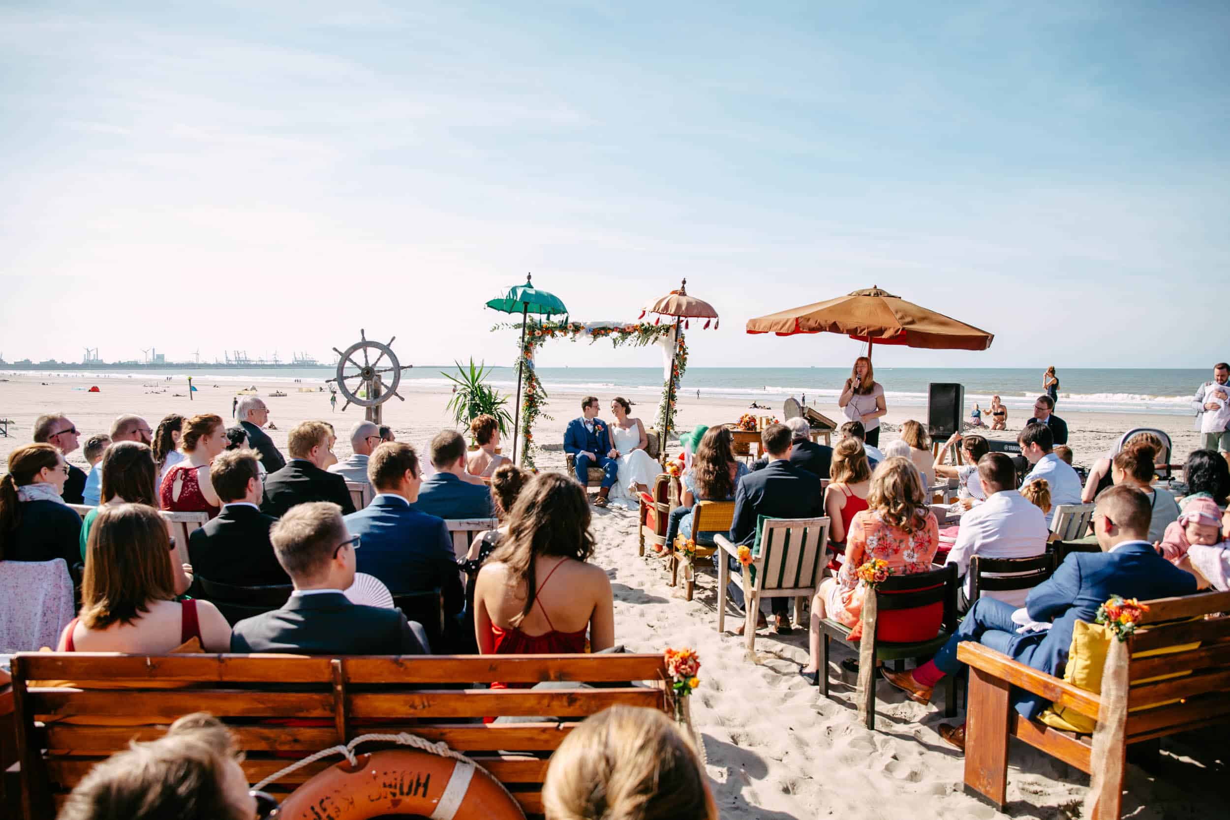 Een strandhuwelijksceremonie, compleet met stoelen en parasols, waarin de elementen van een perfect feest aan zee worden getoond.