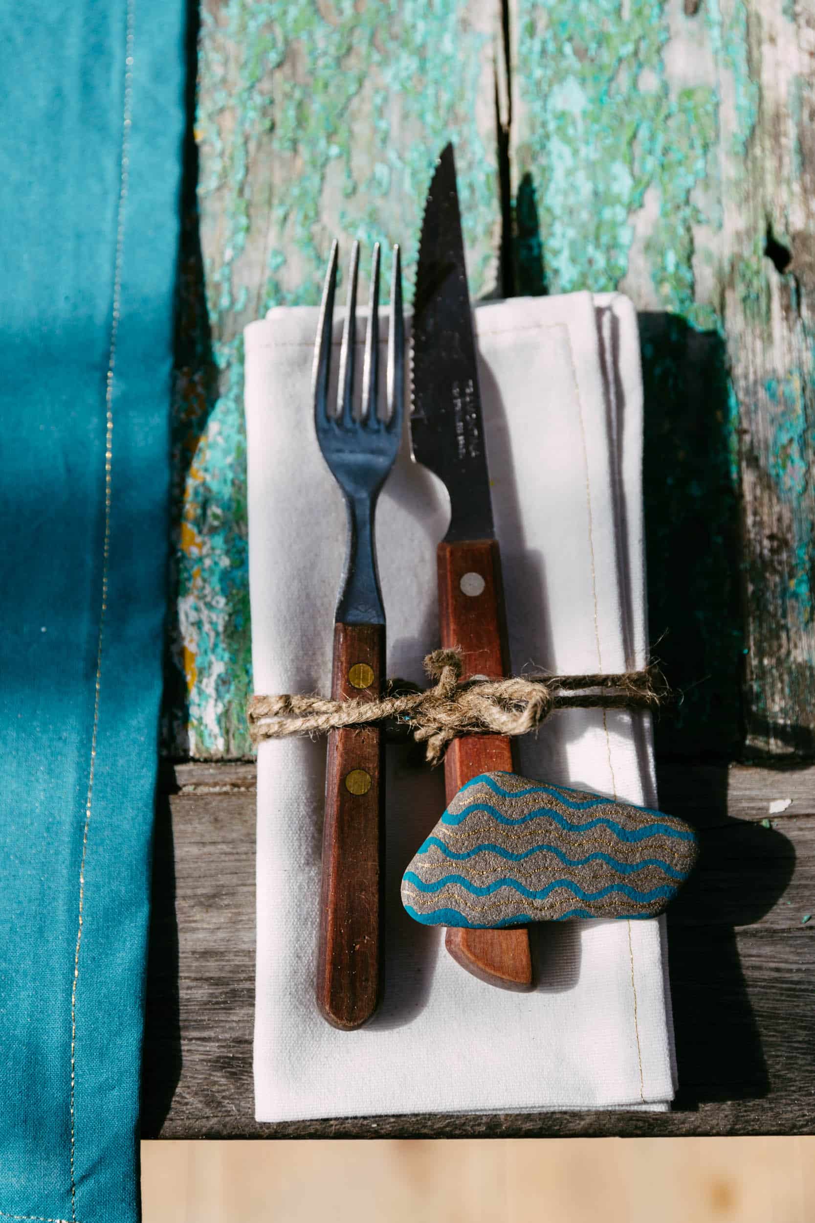 A beach-themed napkin with a fork and knife on top, designed with elements of the coast.