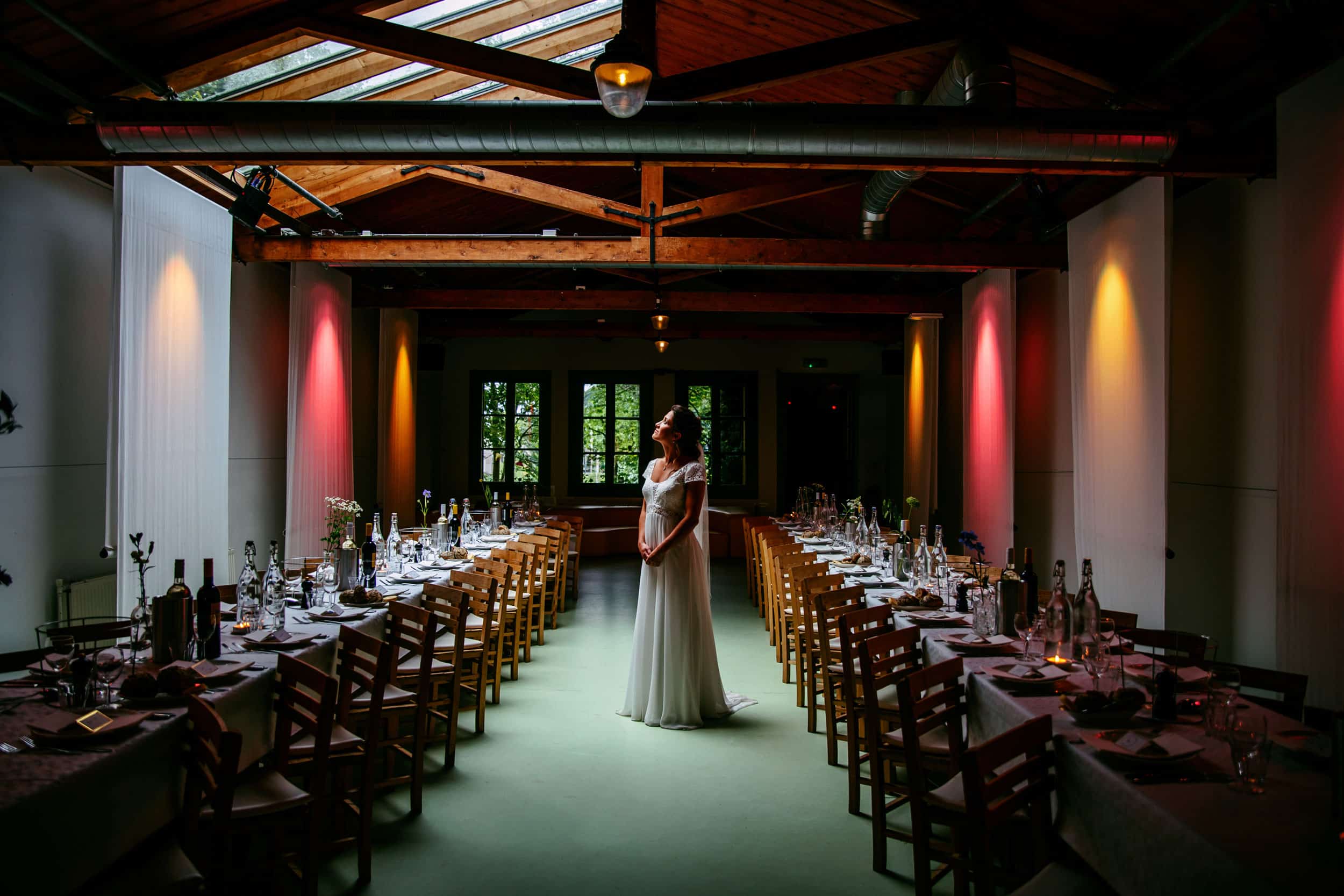 A bride in a white dress standing in The Empire of the Emperor, a dark room transformed into an enchanting wedding venue.
