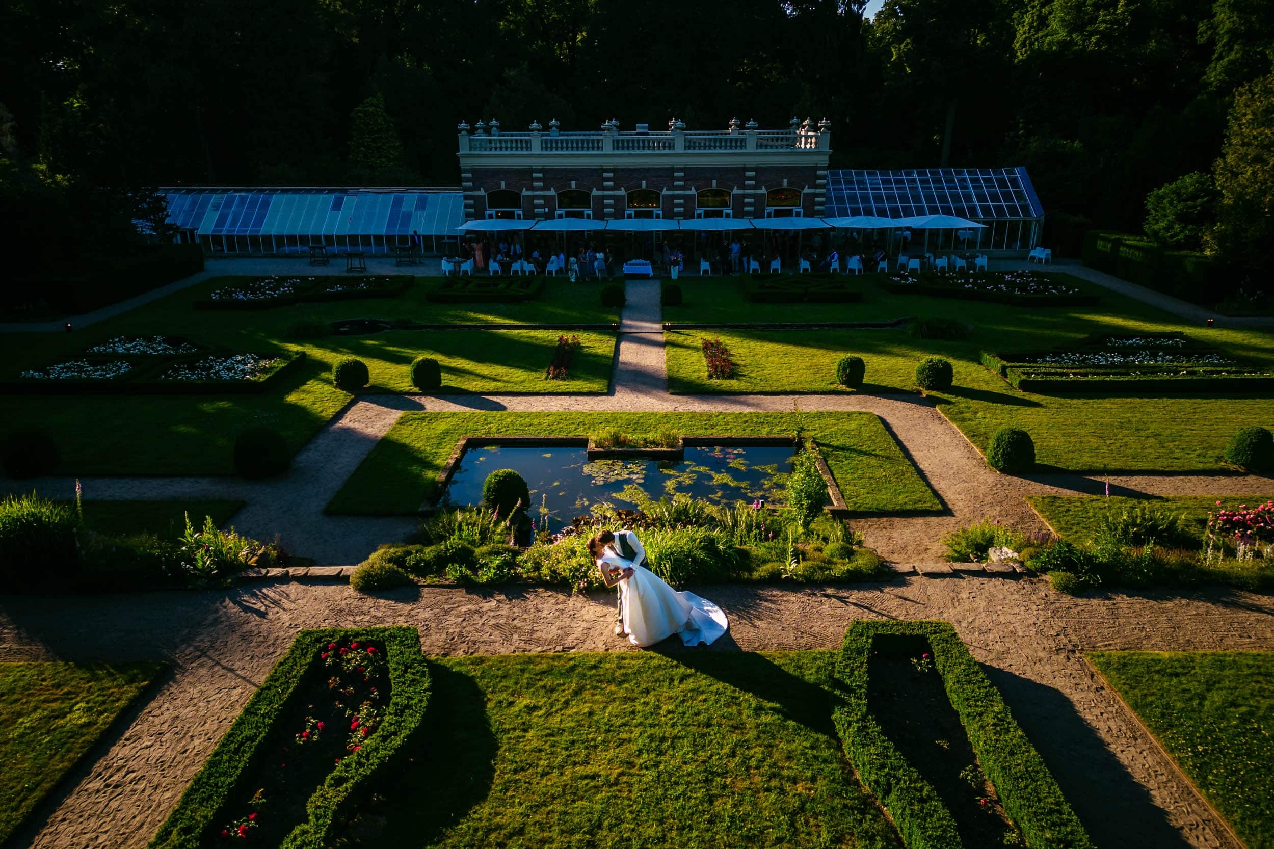 A bride and groom stand in front of the garden of Groot Warnsborn Estate.