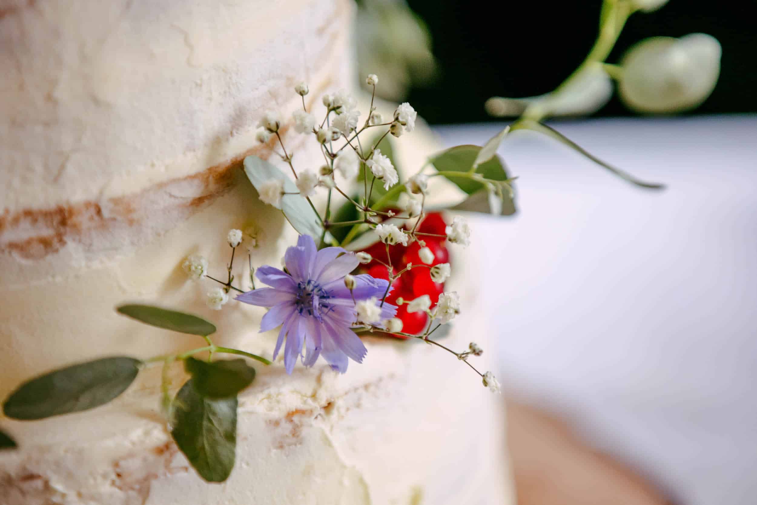 A close-up of a wedding cake with flowers on top.