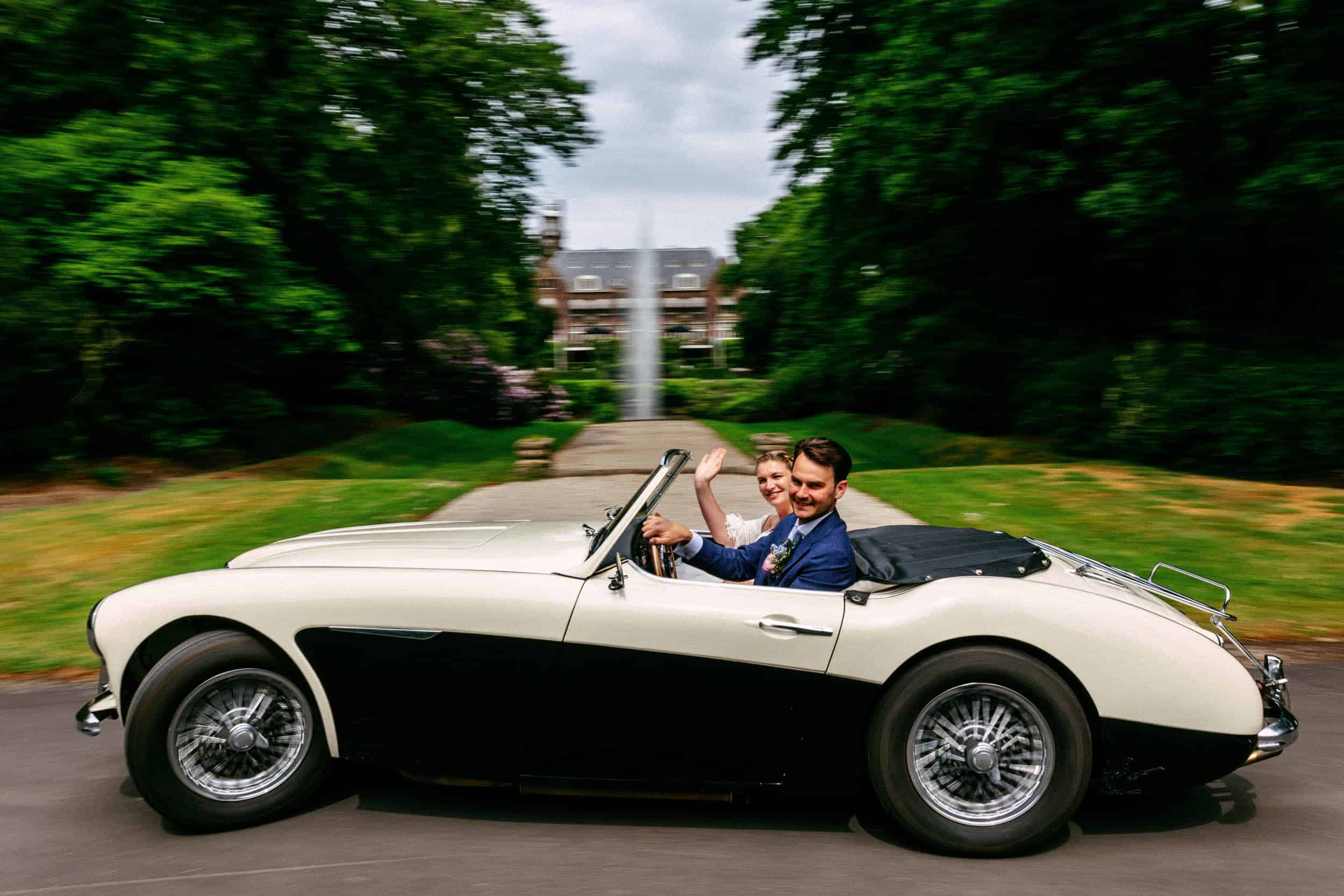 A man and a woman in a vintage sports car.