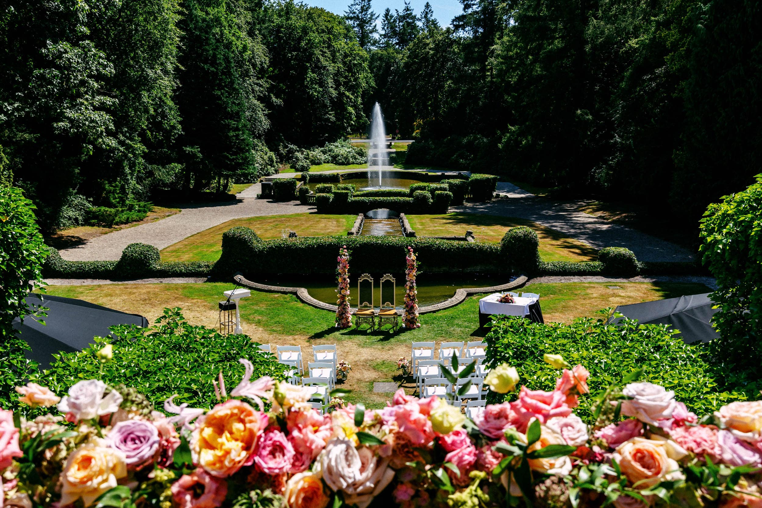 Een bruiloft in een tuin met een fontein en bloemen.