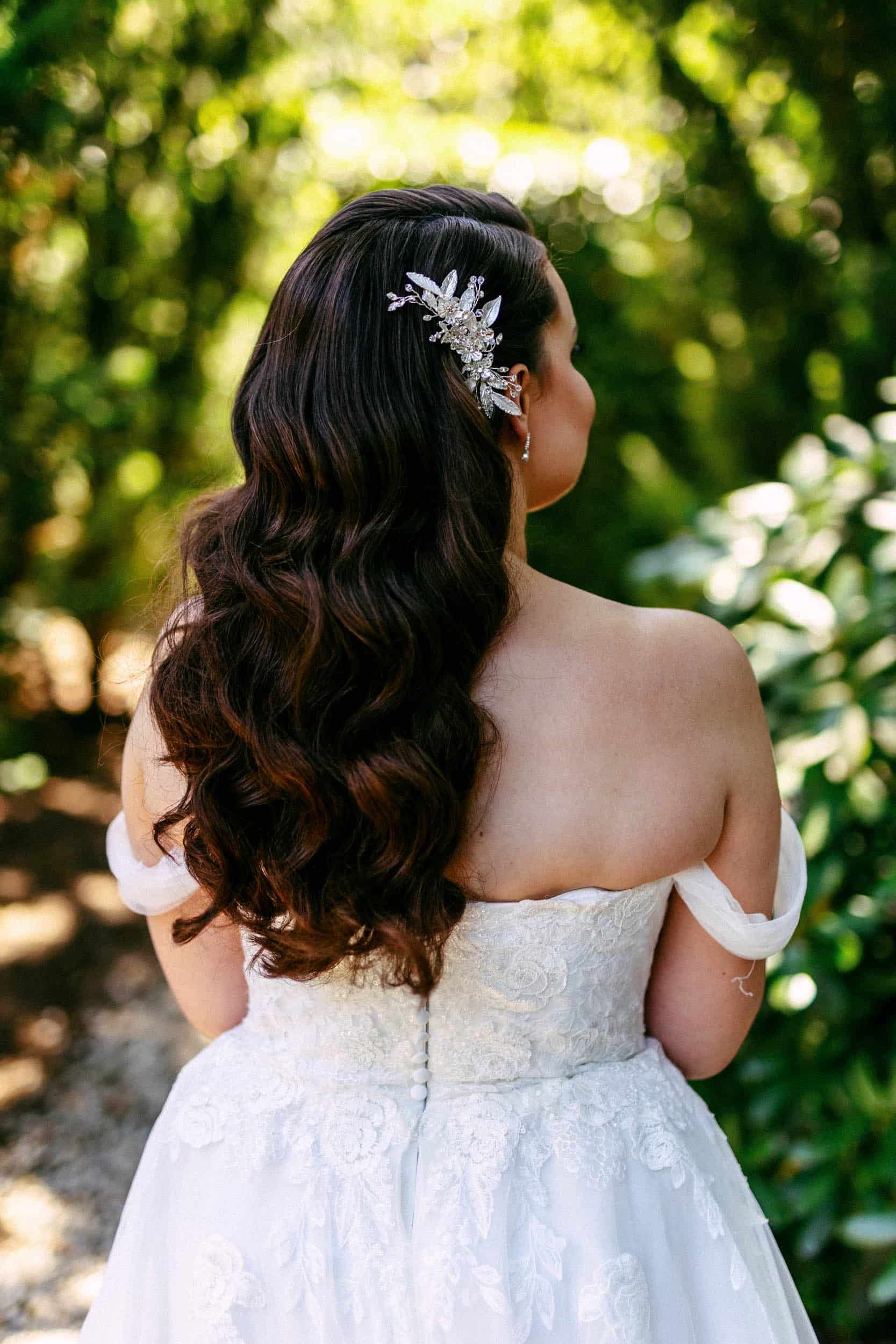 De achterkant van een bruid in trouwjurk die door het bos loopt.