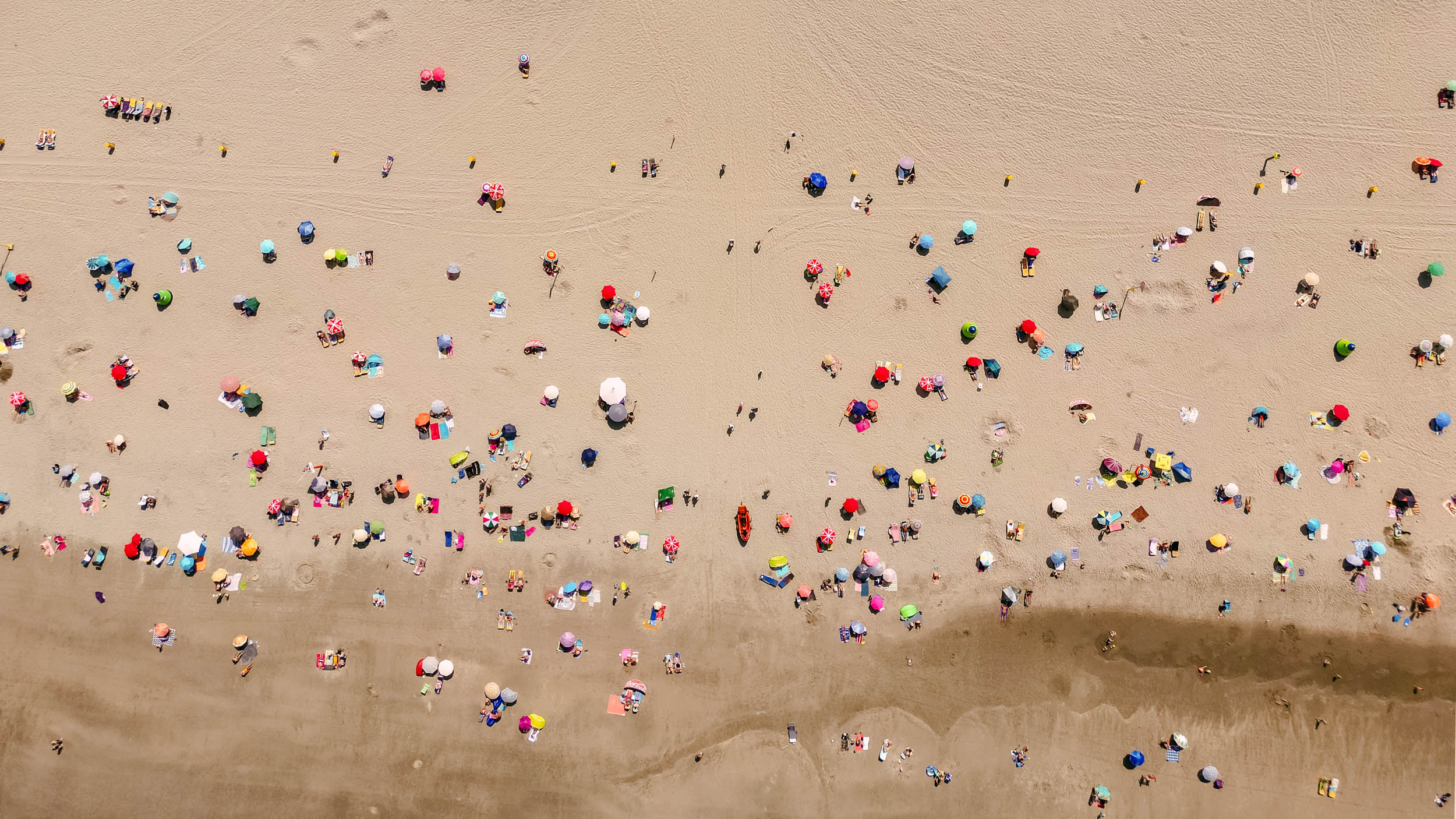 Een groep mensen op een strand met parasols.