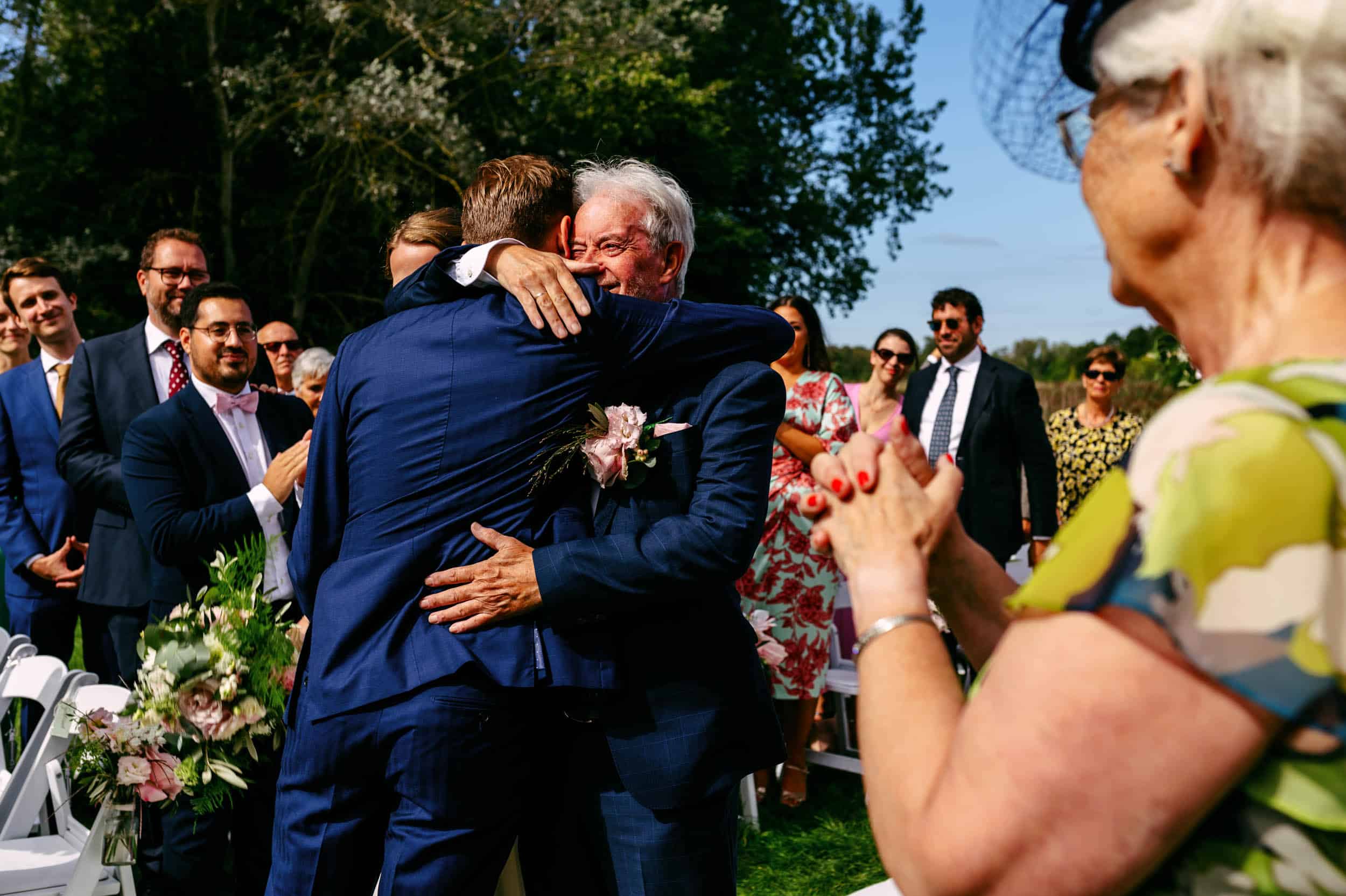 A man hugs father during a Wedding Photo at the perfect wedding ceremony.