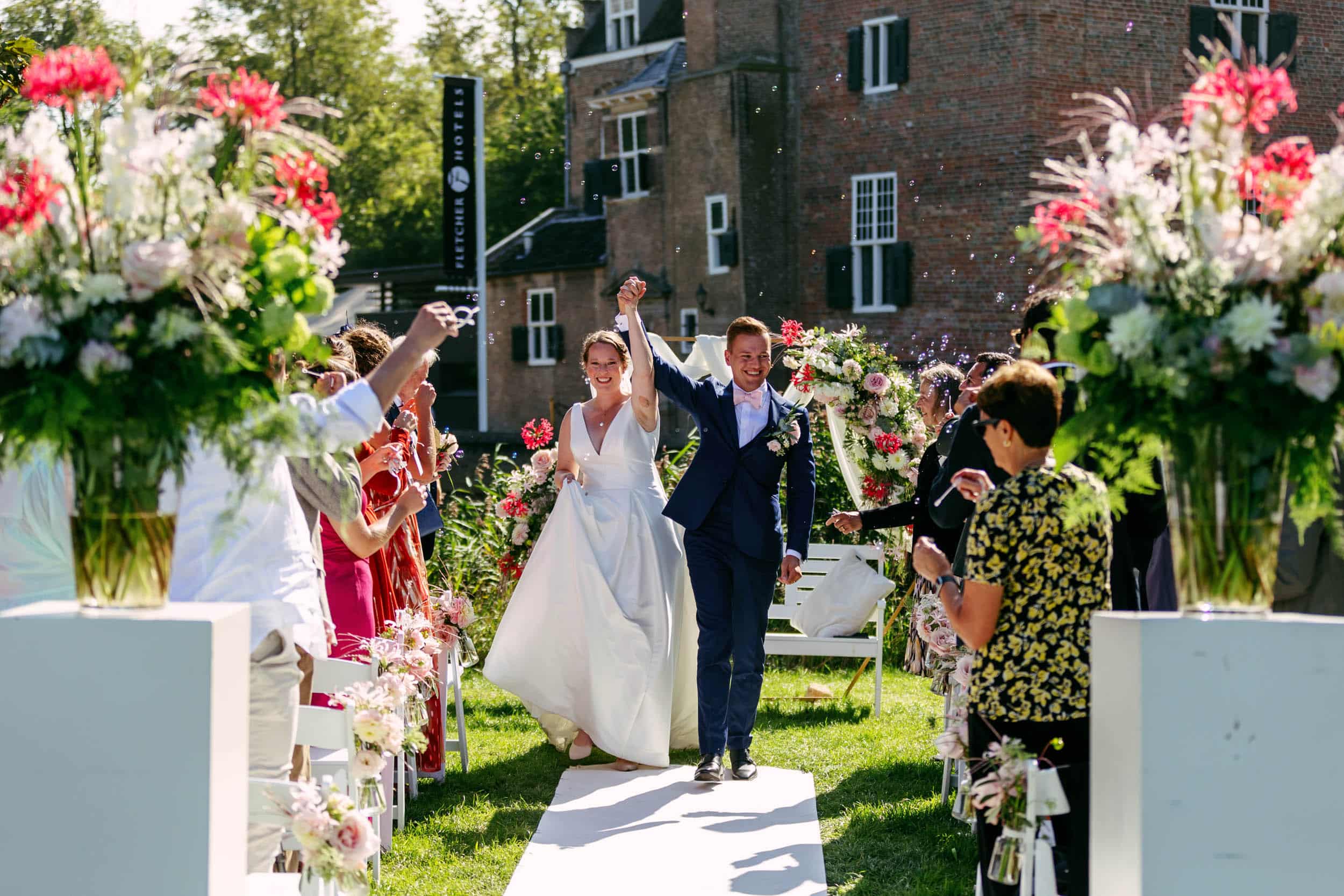 De perfecte bruiloft vastgelegd door een trouwfotograaf met een prachtige Trouwfoto van het bruidspaar dat door het gangpad loopt.