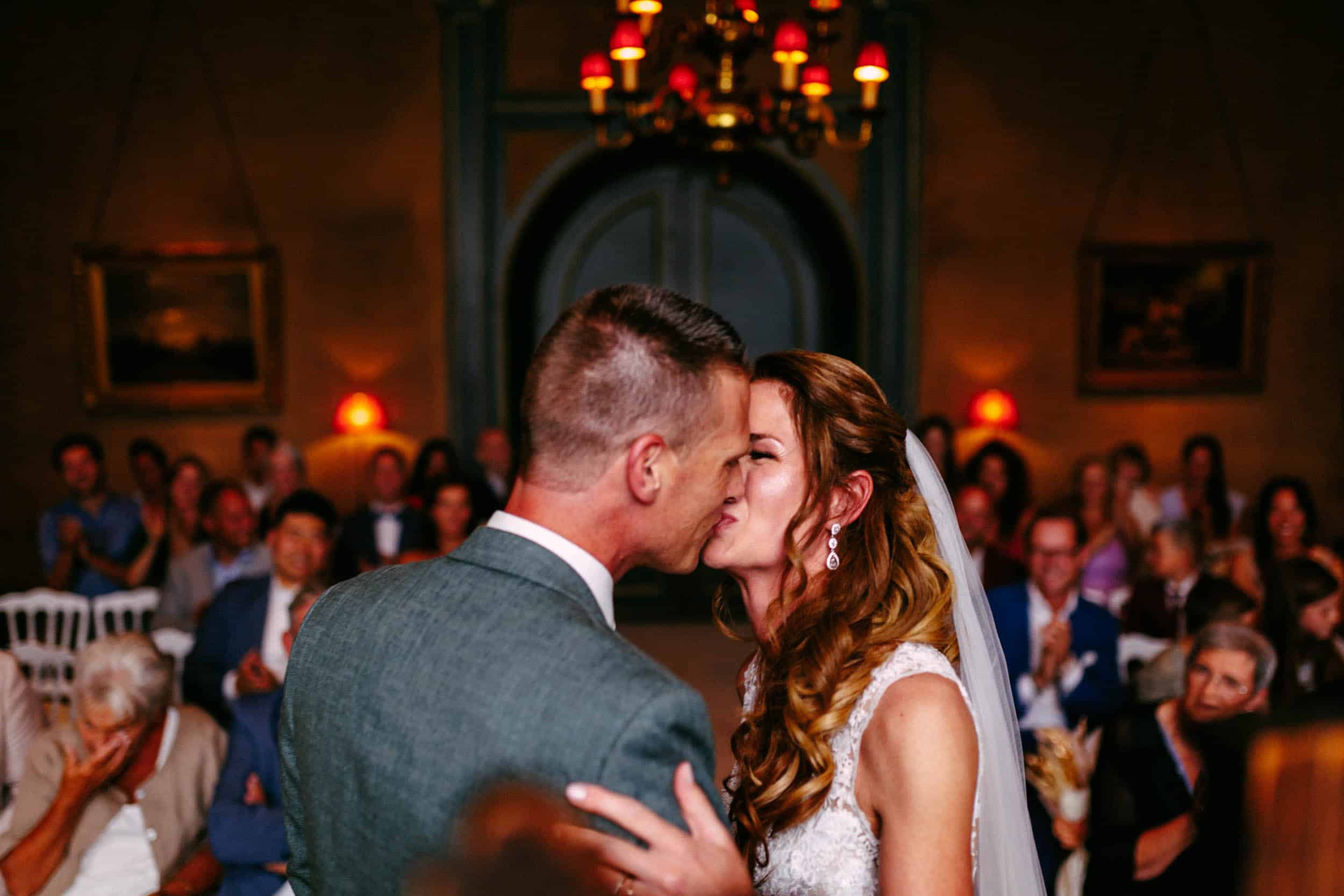 Het perfecte huwelijksmoment vastgelegd: een kus van bruid en bruidegom tijdens hun huwelijksceremonie, prachtig gefotografeerd door een getalenteerde trouwfotograaf.
