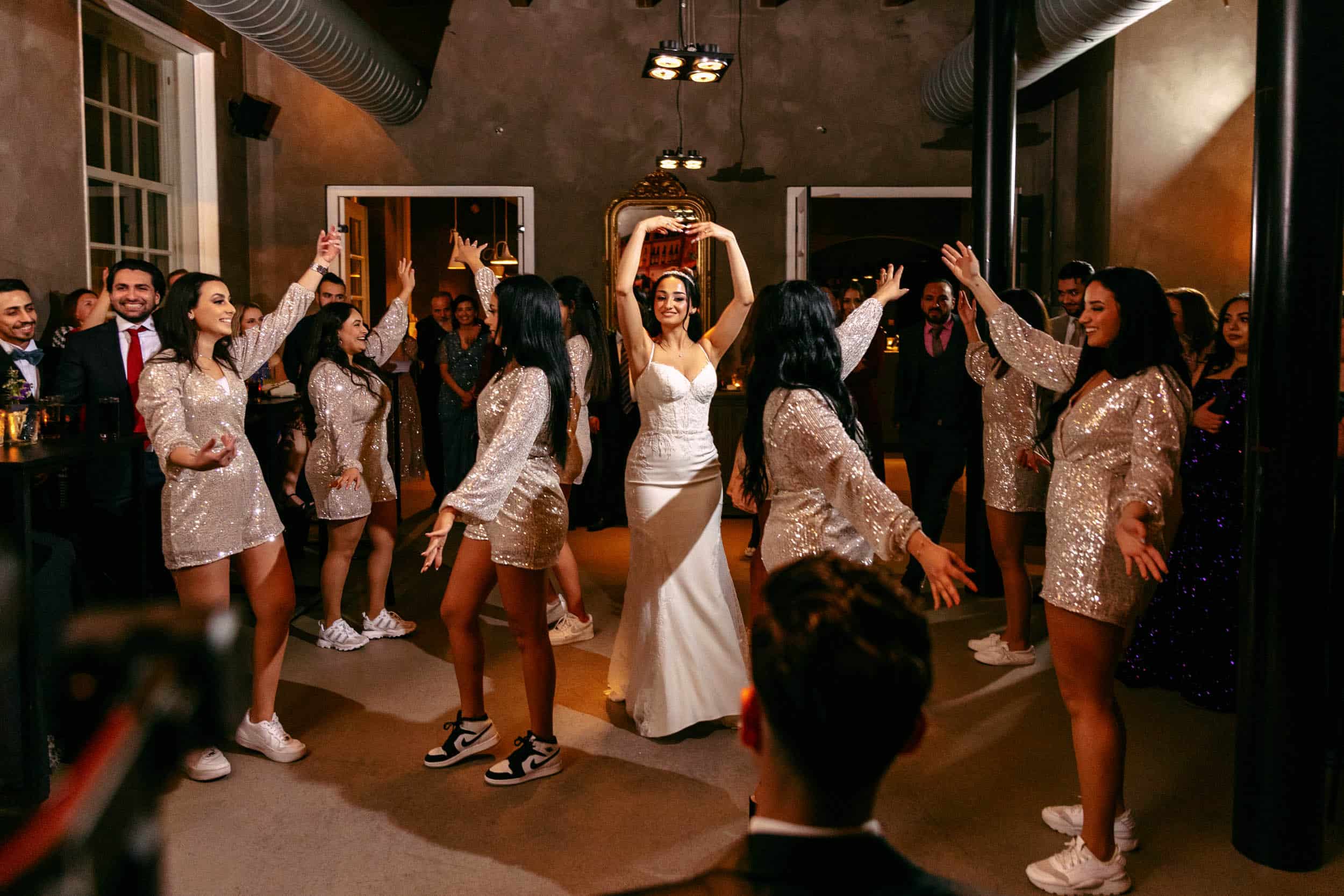 Een bruid en haar bruidsmeisjes dansen op een huwelijksreceptie.