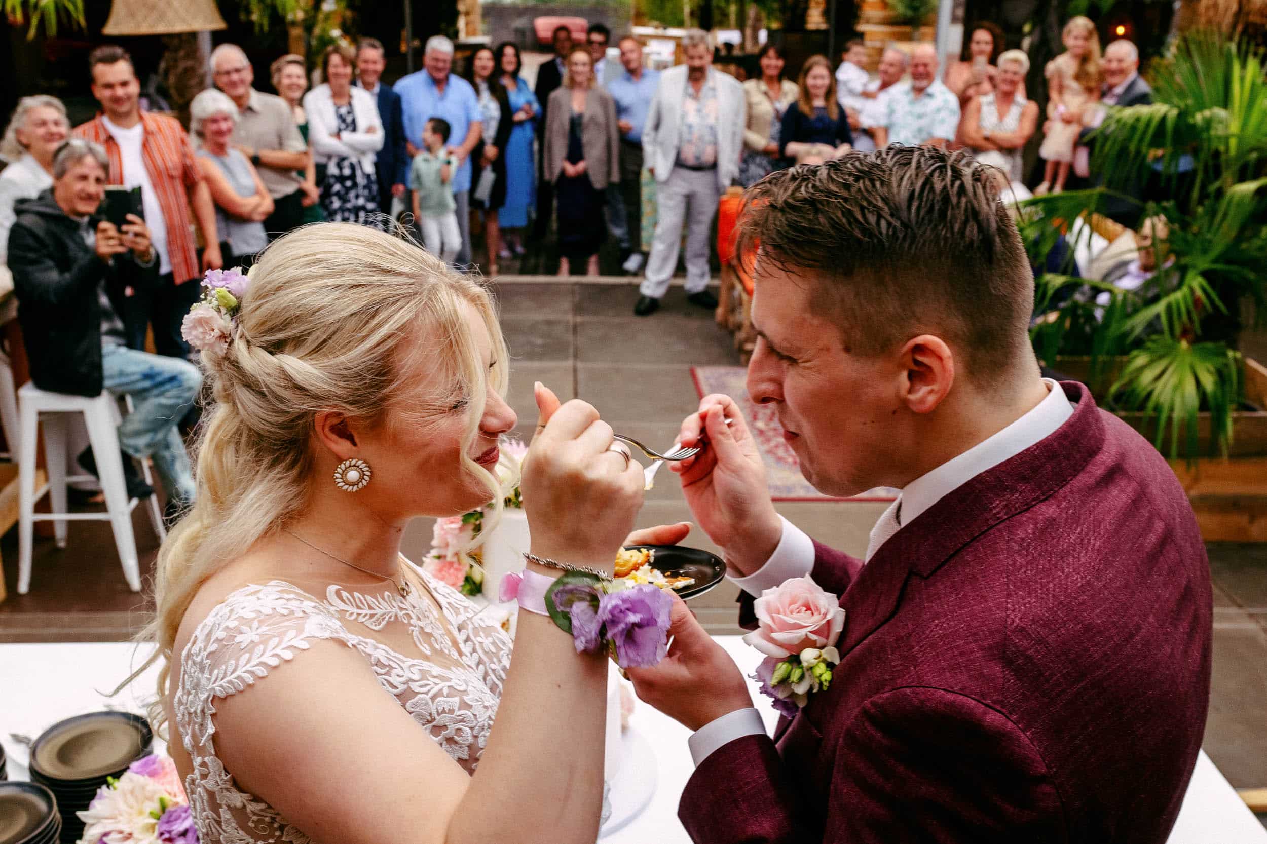 Een bruid en bruidegom delen een oprecht moment waarop ze elkaar voeden op de perfecte bruiloft, vastgelegd door een getalenteerde trouwfotograaf voor de ultieme Trouwfoto.