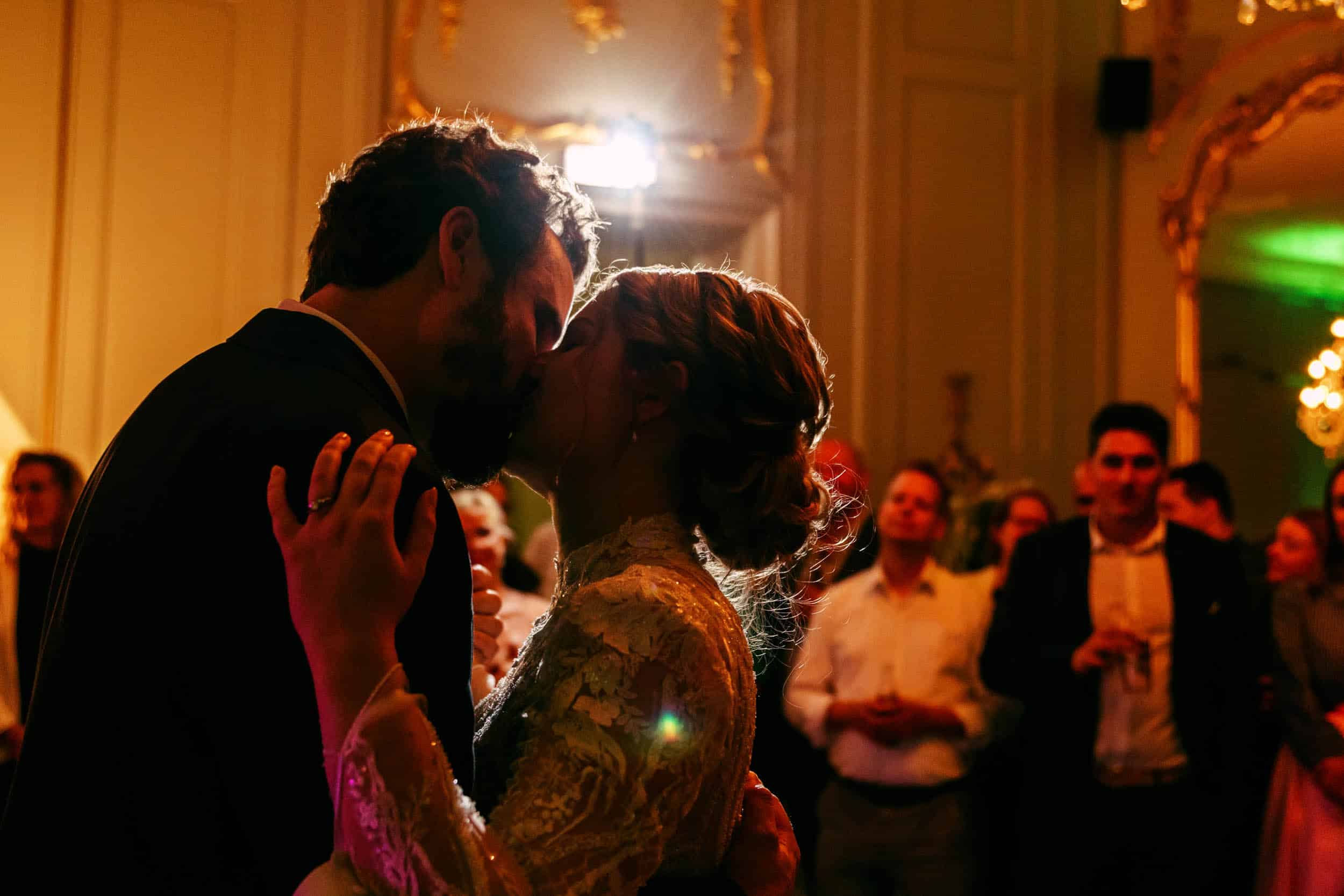 De perfecte trouwfoto van een bruid en bruidegom die een kus delen in een balzaal, vastgelegd door de trouwfotograaf.